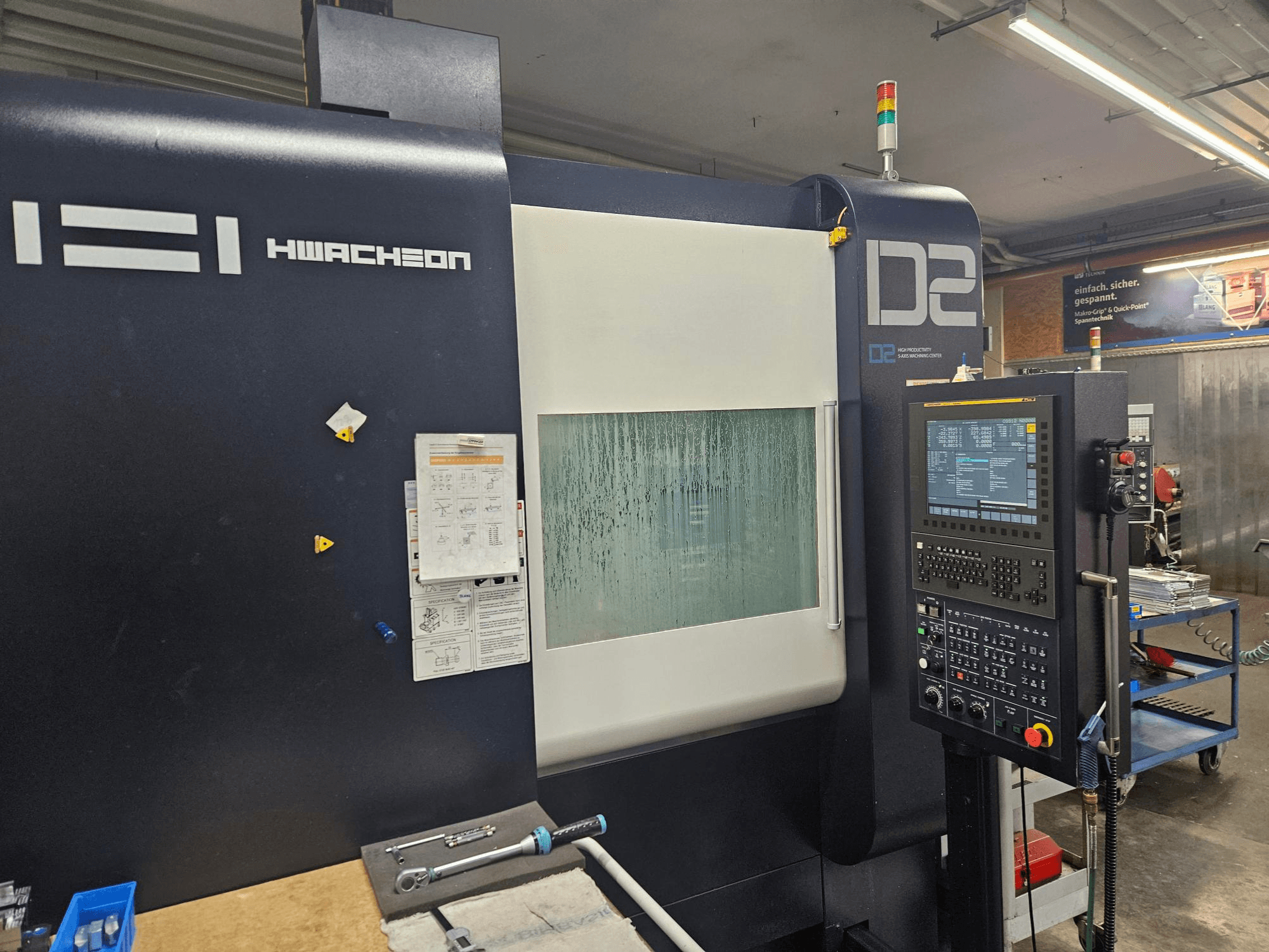 HWACHEON D2-5AX 12k verticaal bewerkingscentrum, vooraanzicht met bedieningspaneel en beslagen kijkvenster.
