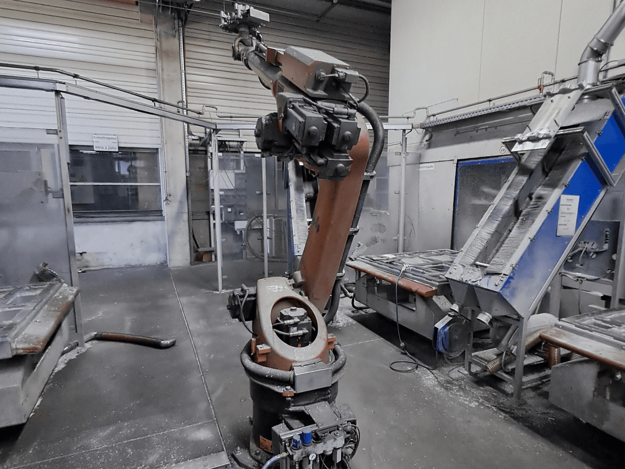 KUKA KR 30L16-2-robotarm in een werkplaatsomgeving, vooraanzicht, met zichtbaar stof en machines op de achtergrond.