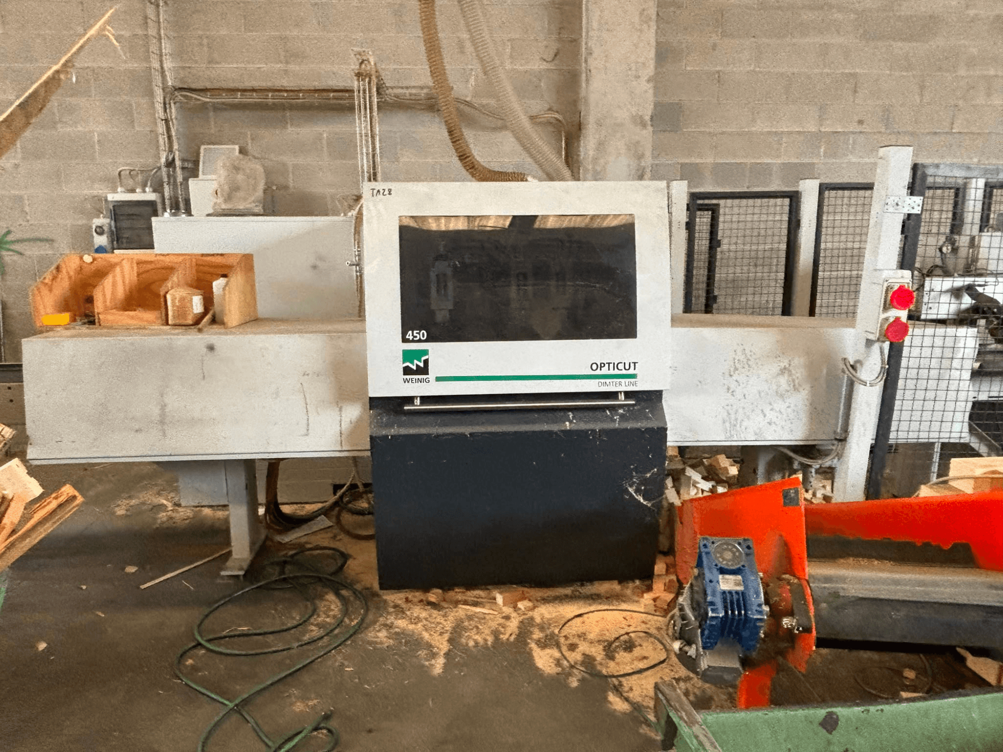 WEINIG OptiCut 450 optimaliserende afkortzaag, vooraanzicht, met weergave van het bedieningspaneel, het zaaggebied en de stukken hout op de tafel.
