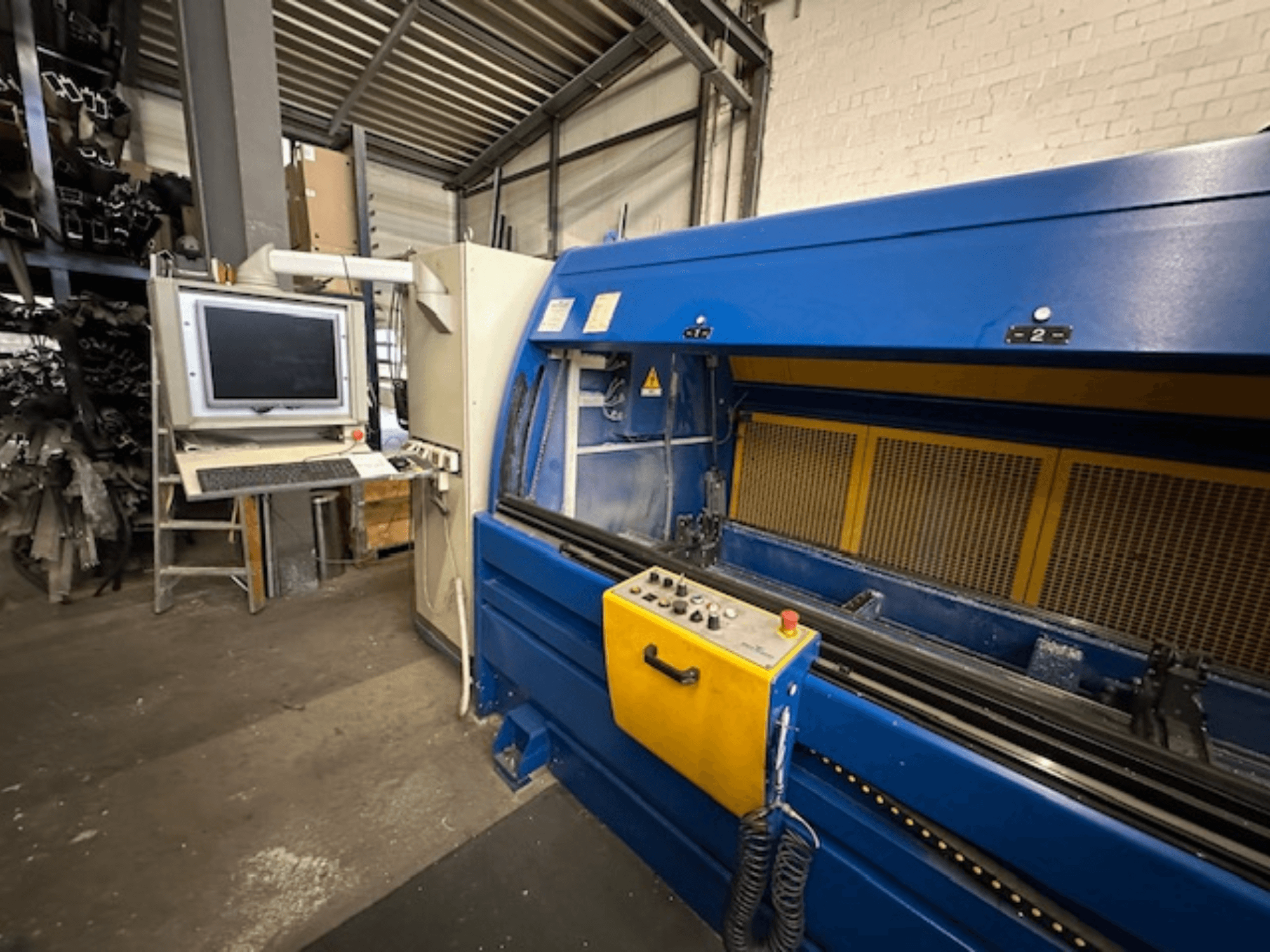 Vooraanzicht van het SCHÜCO Profilbearbeitungscenter 299 650, een universeel bewerkingscentrum met besturingen en computerwerkstation.