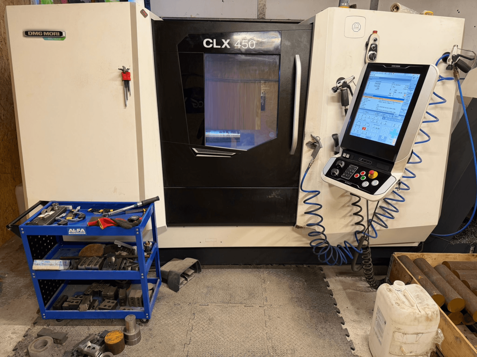 DMG MORI CLX 450 V3 horizontale draaimachine vooraanzicht, met bedieningspaneel en nabijgelegen gereedschapswagen met apparatuur.