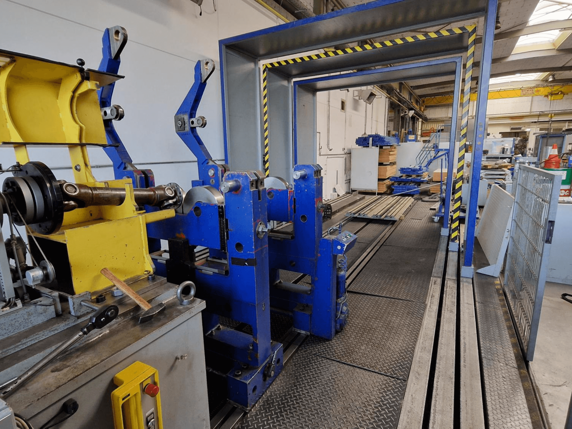 SCHENCK HM 70U BU-bewerkingsmachine, zijaanzicht van de blauwe constructie met gele onderdelen en bedieningspaneel in een industriële omgeving.