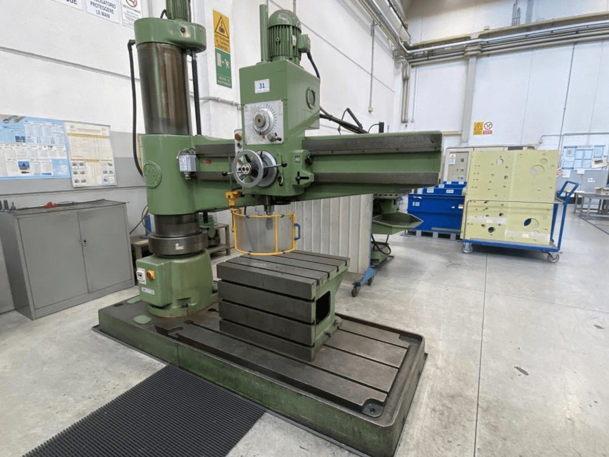 Groene verticale freesmachine met een grote rechthoekige tafel, vooraanzicht, met gereedschap en bedieningspaneel, in een werkplaatsomgeving.
