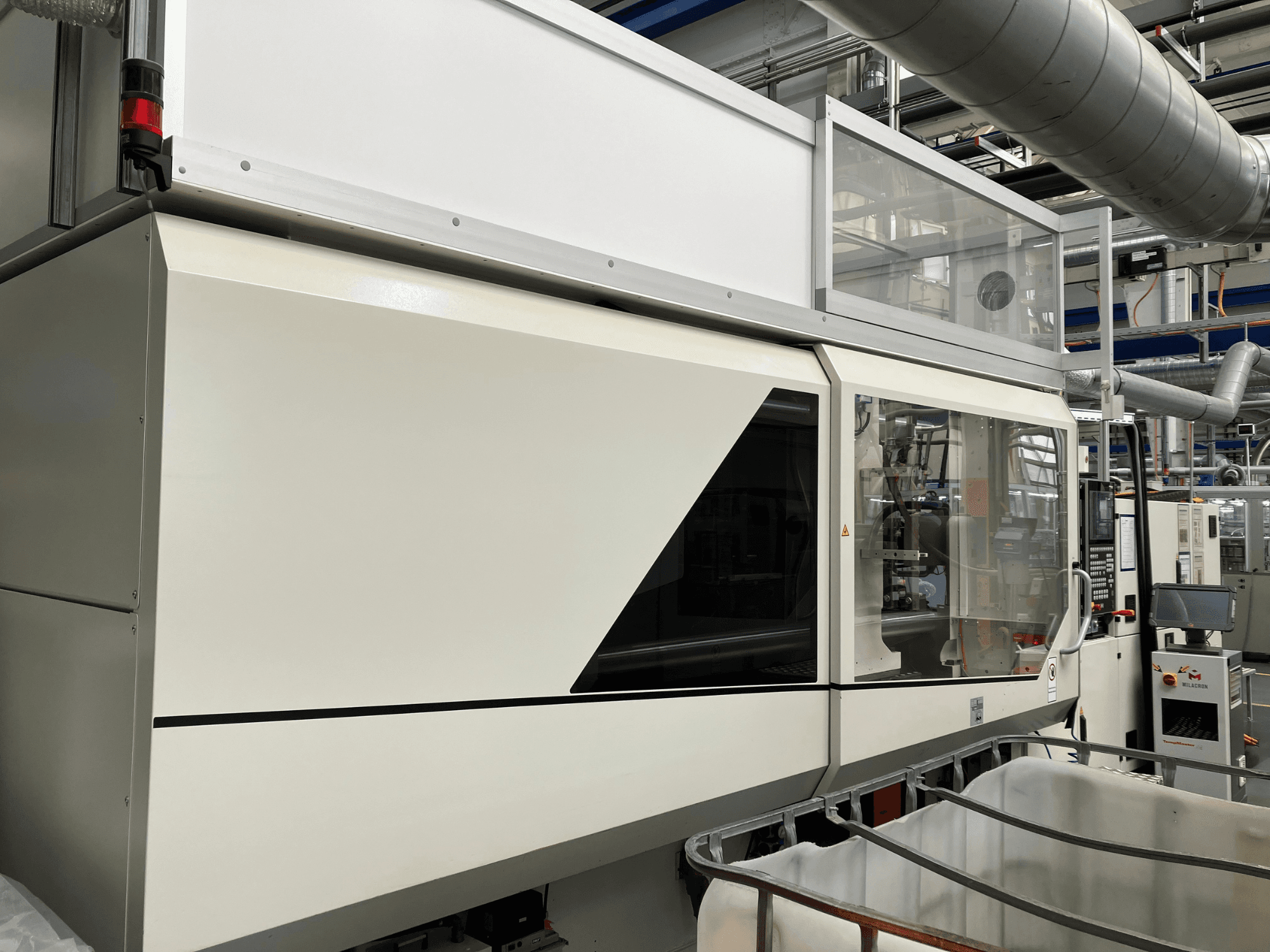 Vooraanzicht van industriële machine, met een slank wit ontwerp, displaypaneel en glazen sectie voor zichtbaarheid van componenten.