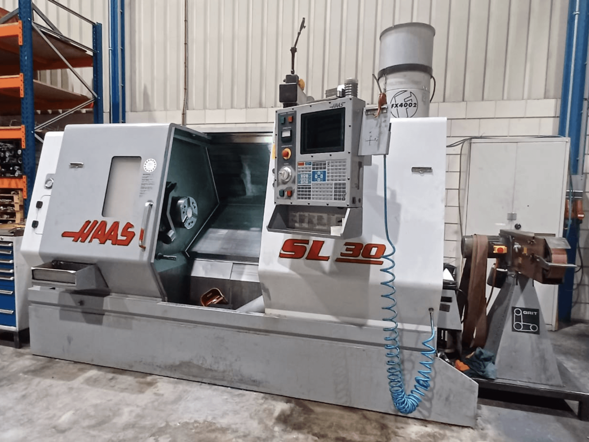 Haas SL 30 CNC draaibank in zijaanzicht, met het bedieningspaneel, het bewerkingsgebied en het geïntegreerde koelvloeistofsysteem voor metaalbewerking.
