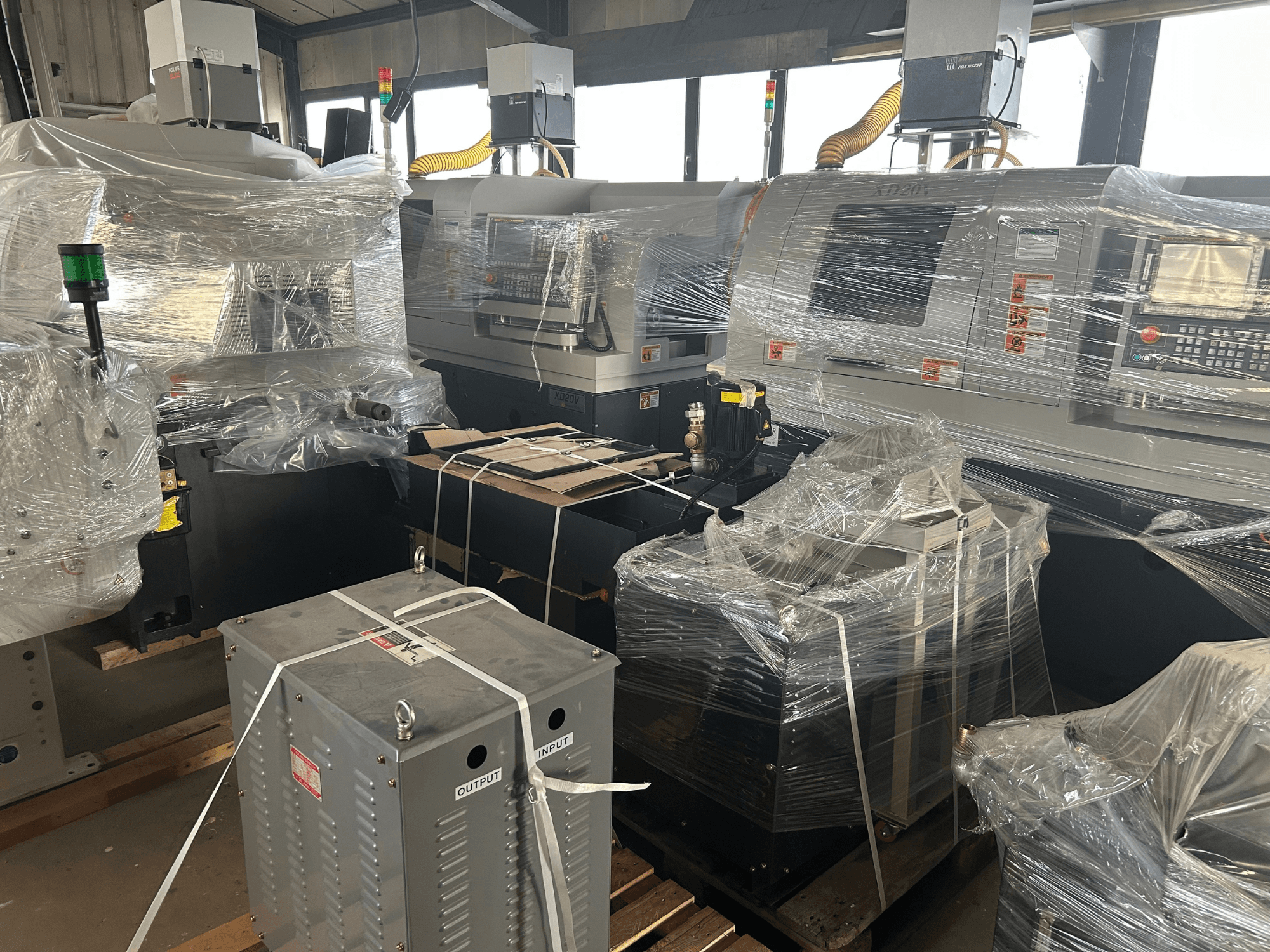 Hanwha XD20V gecombineerde Zwitserse draaimachine, gedeeltelijk ingepakt, in zijaanzicht met zichtbare bedieningselementen en machineonderdelen.