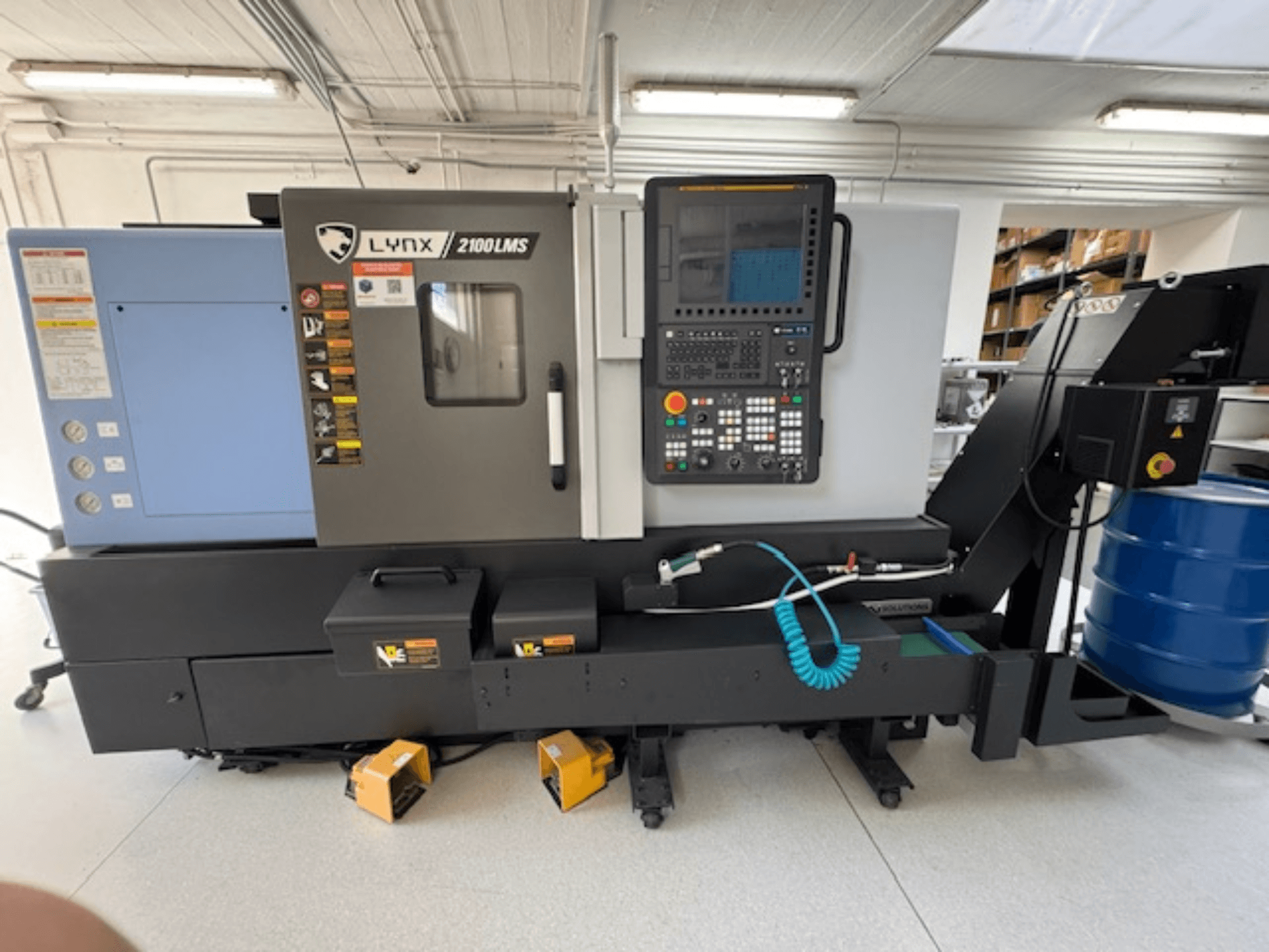 DOOSAN LYNX 2100LMSA horizontale draaimachine, vooraanzicht, met bedieningspaneel, koelvloeistofslang en opbergvakken.
