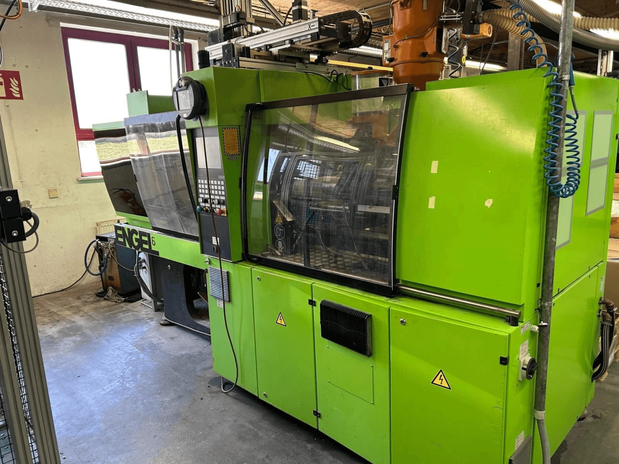 Vooraanzicht van de hydraulische spuitgietmachine Engel VICTORY 330/80 Tech, met een groene behuizing en bedieningspaneel.
