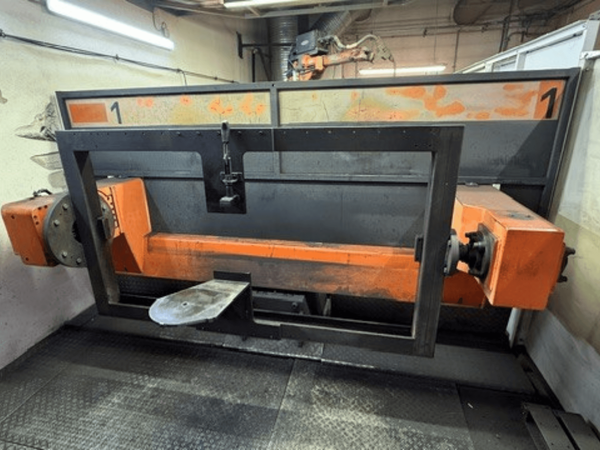 Vooraanzicht van de ABB IRB 2400L-lascel, met een groot robotframe met oranje en zwarte onderdelen in een werkplaatsomgeving.