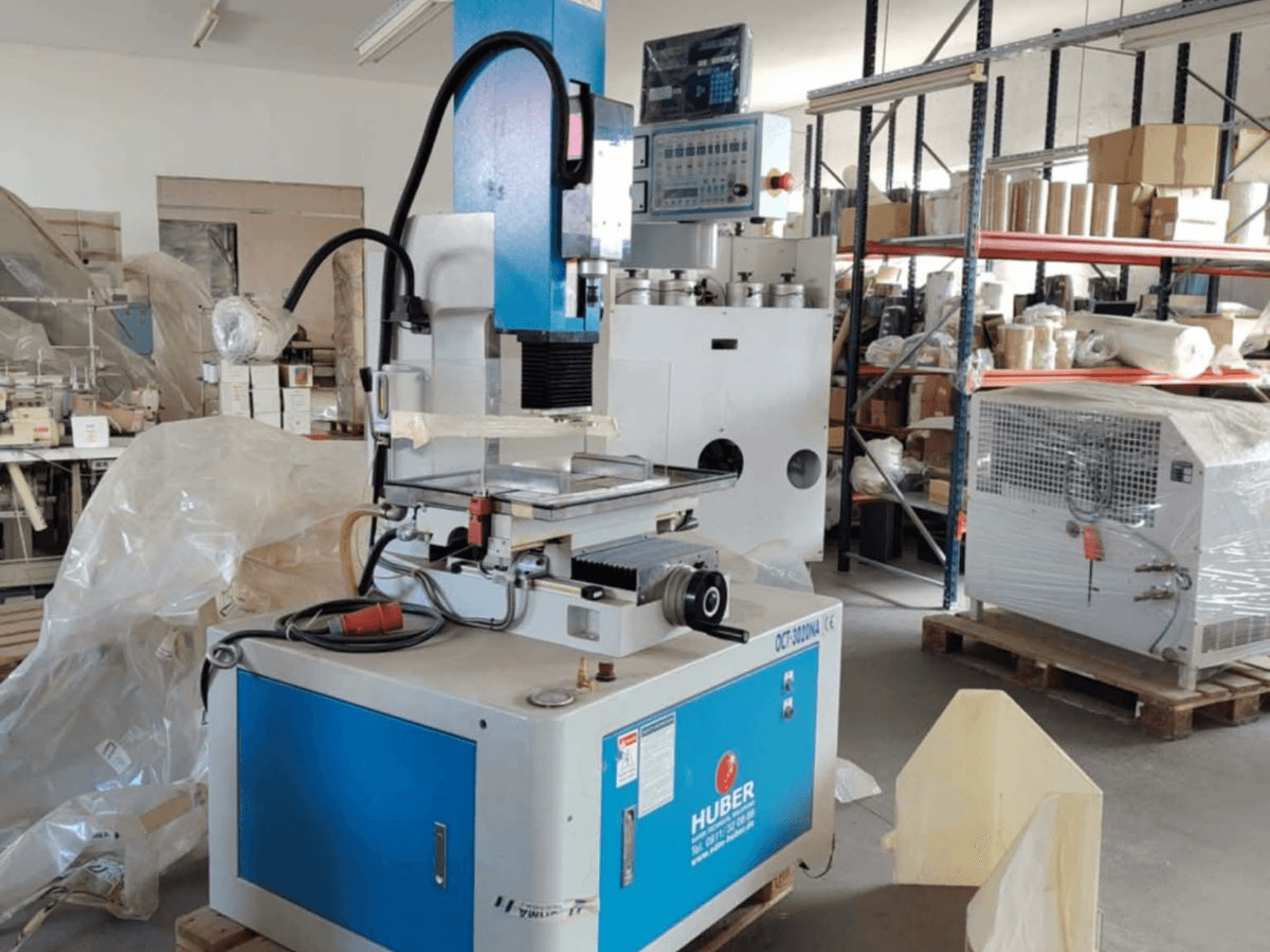 HUBER OCT-3020 NA zinkvonkmachine in een werkplaats, vooraanzicht met blauwe en grijze behuizing, digitale bediening en werkgebied.