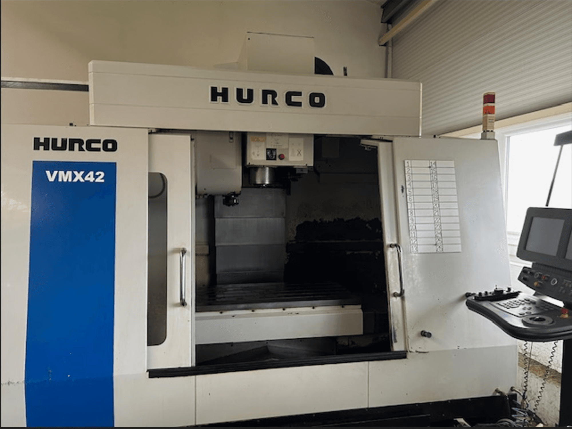 Hurco VMX42 CNC freesmachine, vooraanzicht, met bedieningspaneel en open werkruimte voor verspanende bewerkingen.