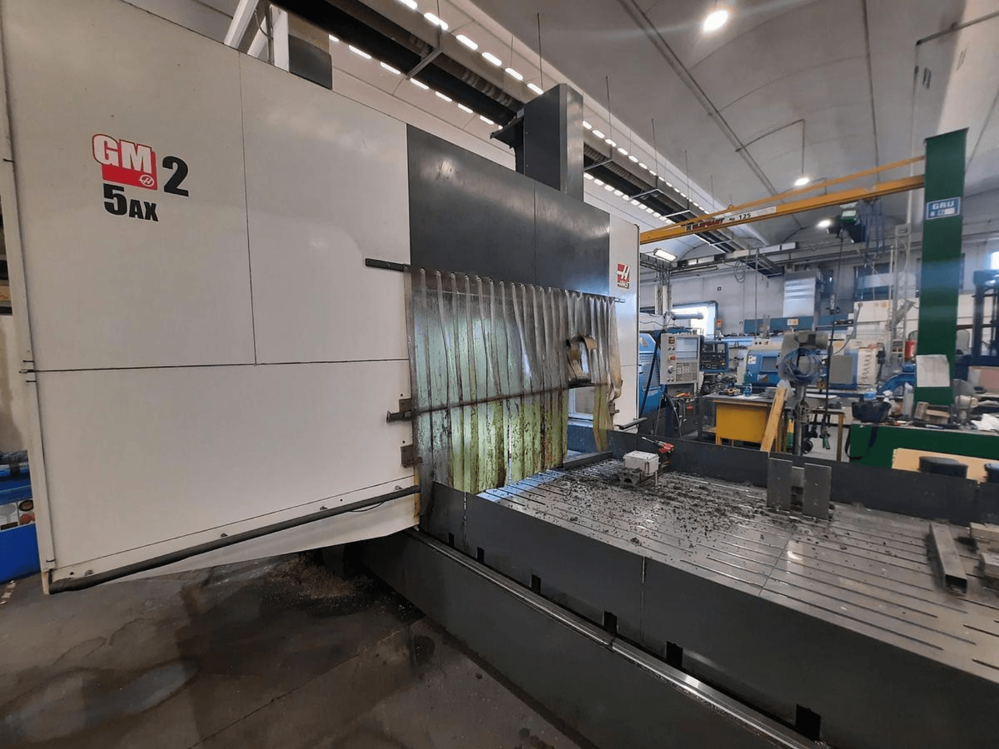 GM 2 5AX CNC machine in een werkplaats, zijaanzicht, met het werkgebied en metaalschilfers op het bedoppervlak.