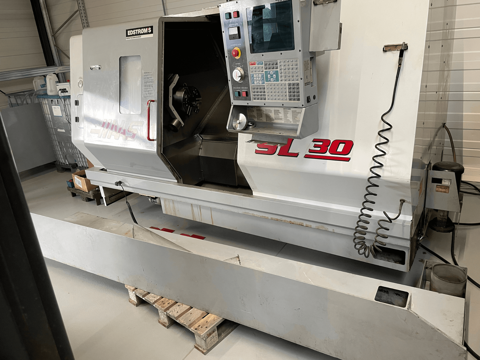 Haas SL 30 CNC draaibank in een werkplaats, zijaanzicht, met bedieningspaneel en open spindel voor bewerkingsopdrachten.