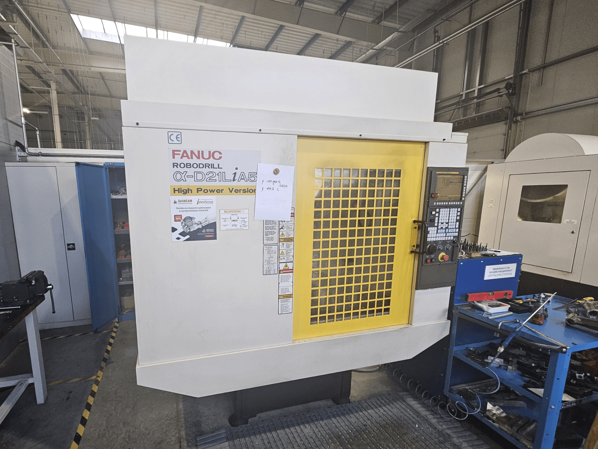 Vooraanzicht van een FANUC Robodrill α-D21LiA5 met gele veiligheidsdeur, bedieningspaneel en werkruimte gereedschap dichtbij.