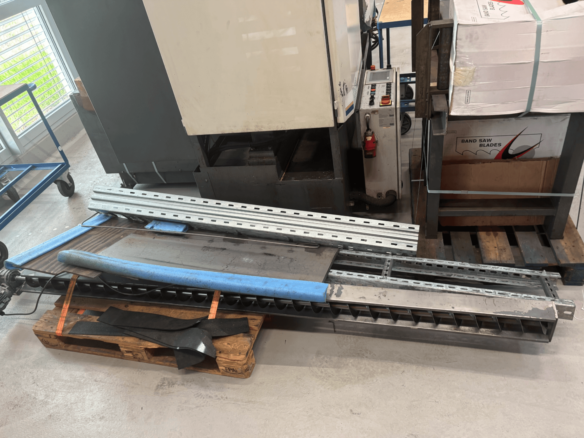 BAUER SA 430 ZA metalen lintzaag getoond vanaf de zijkant, met metalen frame en onderdelen op een houten pallet.