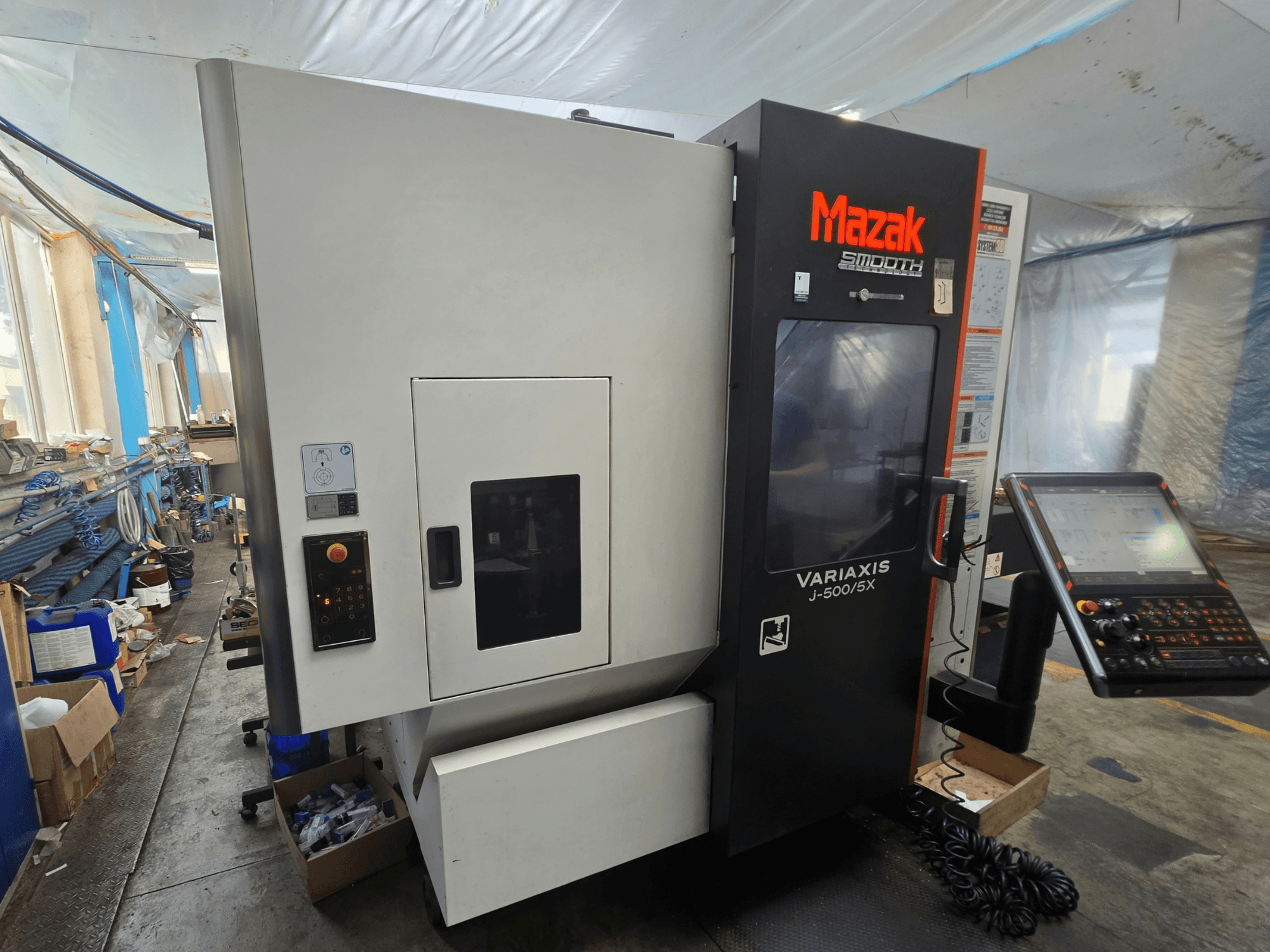 Mazak VARIAXIS J-500/5X verticaal bewerkingscentrum, zijaanzicht met bedieningselementen en display, geplaatst in een werkplaatsomgeving.