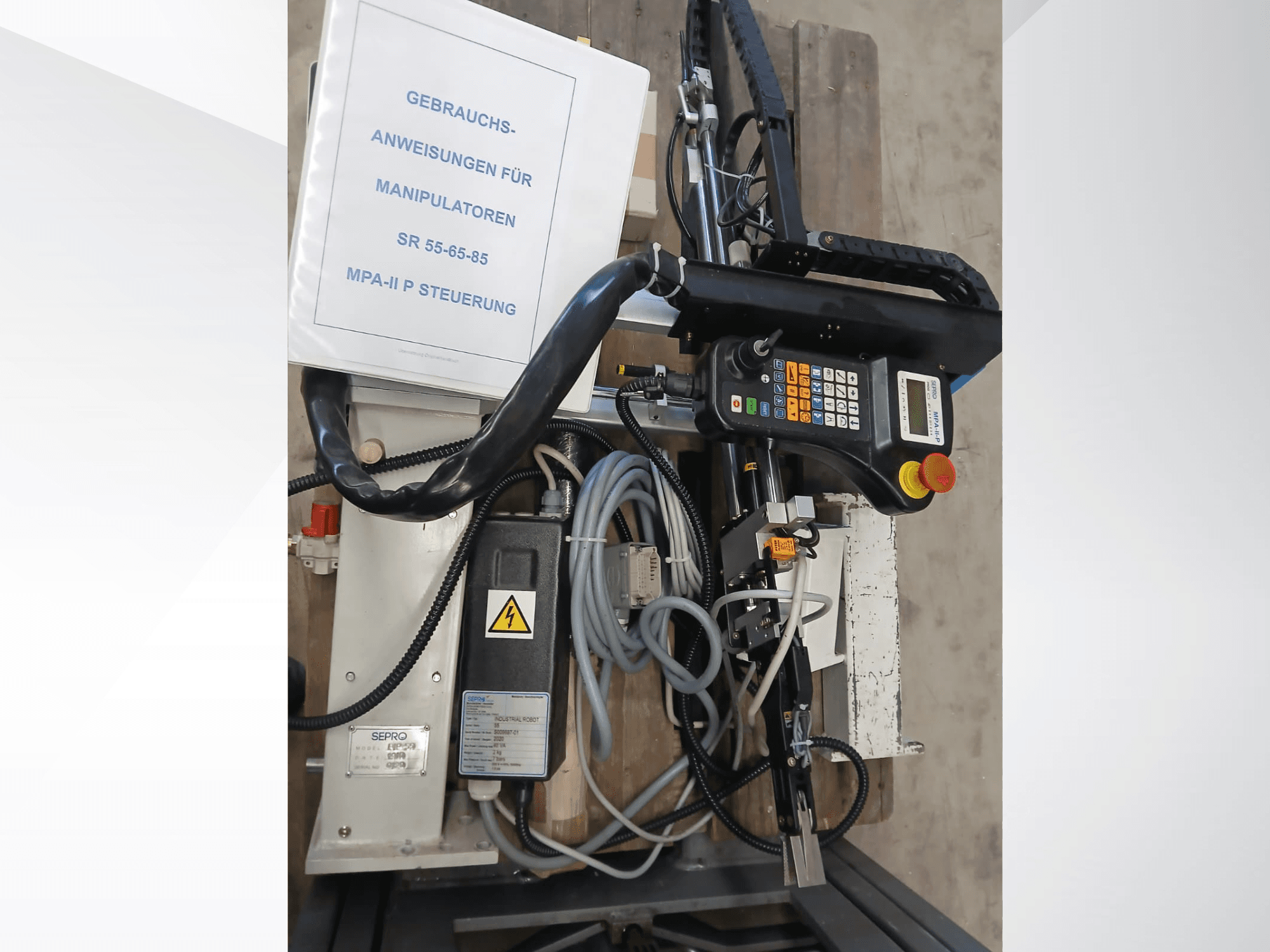 Sepro PIP-55 Gantry Robot bedieningspaneel en componenten, gezien vanaf de zijkant, met de gebruikershandleiding zichtbaar.