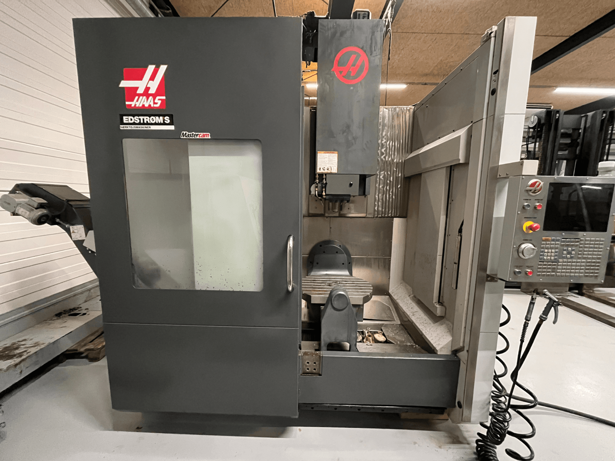 Vooraanzicht van de Haas EDSTROM S CNC machine met het bedieningspaneel, de spindelkop en de bewerkingstafel.