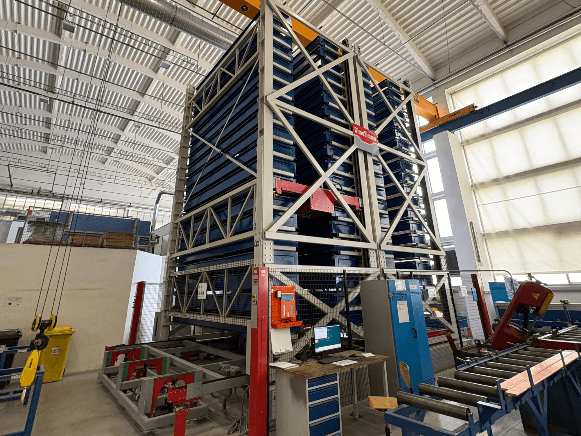 DimaSimma EMS-30 TWIN plaatbewerkingsmachine in een werkplaats, vooraanzicht met gestapelde blauwe platen en bedieningsstation zichtbaar.