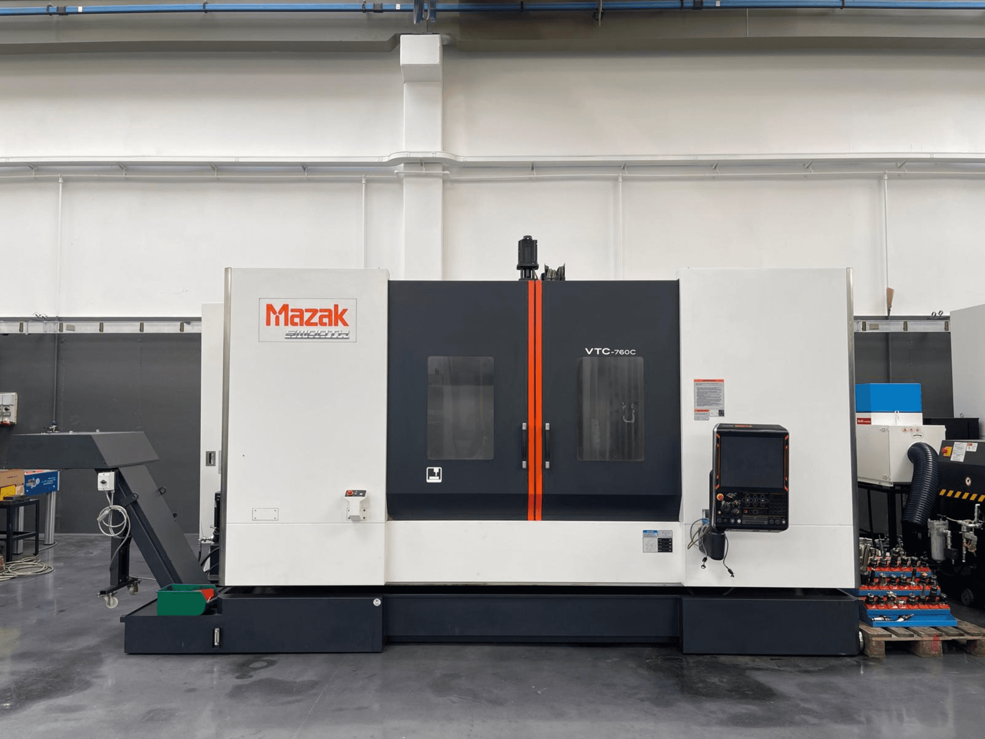 Mazak VTC 760C verticaal bewerkingscentrum, zijaanzicht van de bedieningselementen, witte en zwarte buitenkant en oranje accenten.