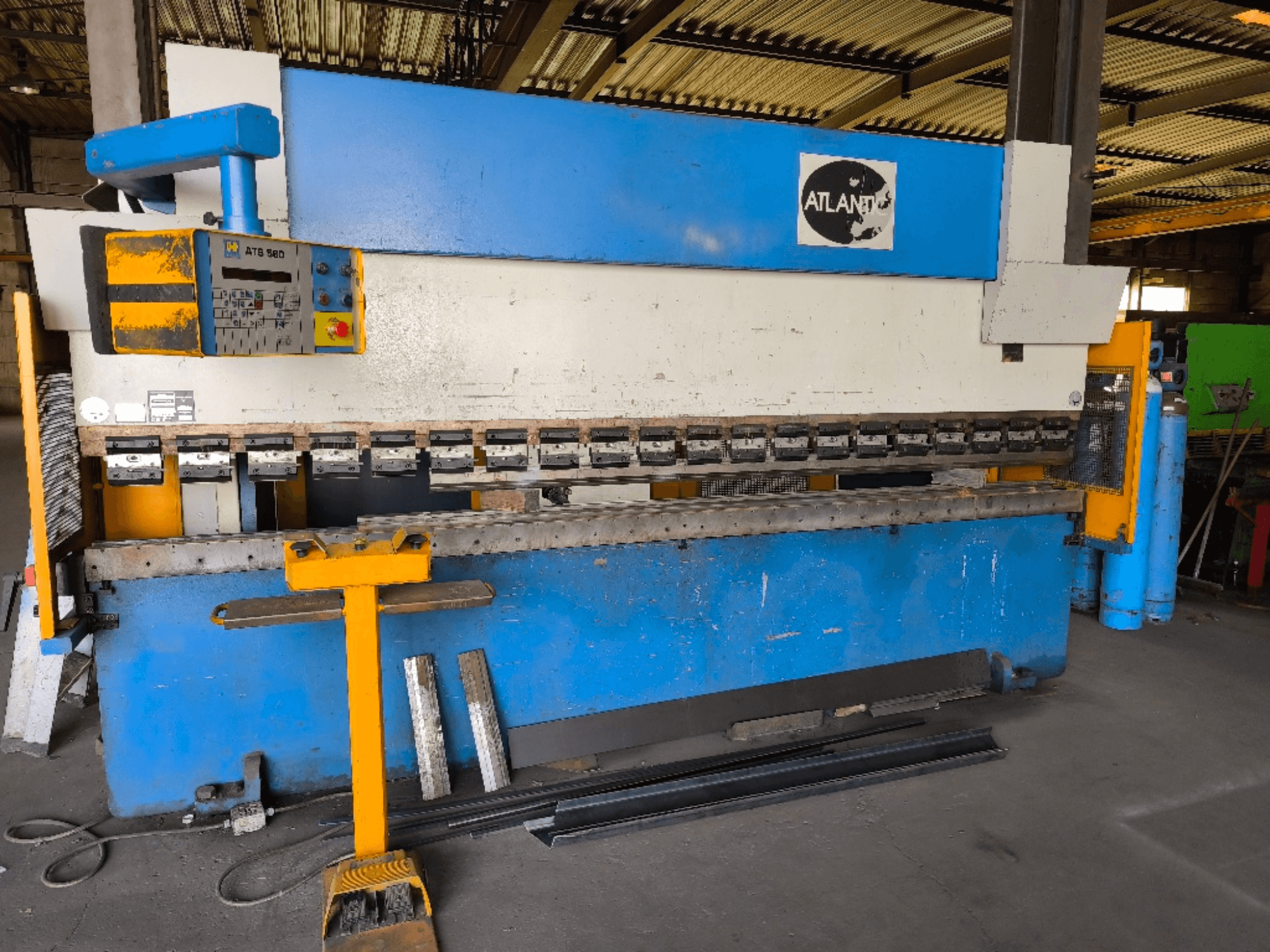 Vooraanzicht van de ATLANTIC HPES-40-135 kantpers, met het bedieningspaneel, de buiggereedschappen en metalen werkstukken ernaast.