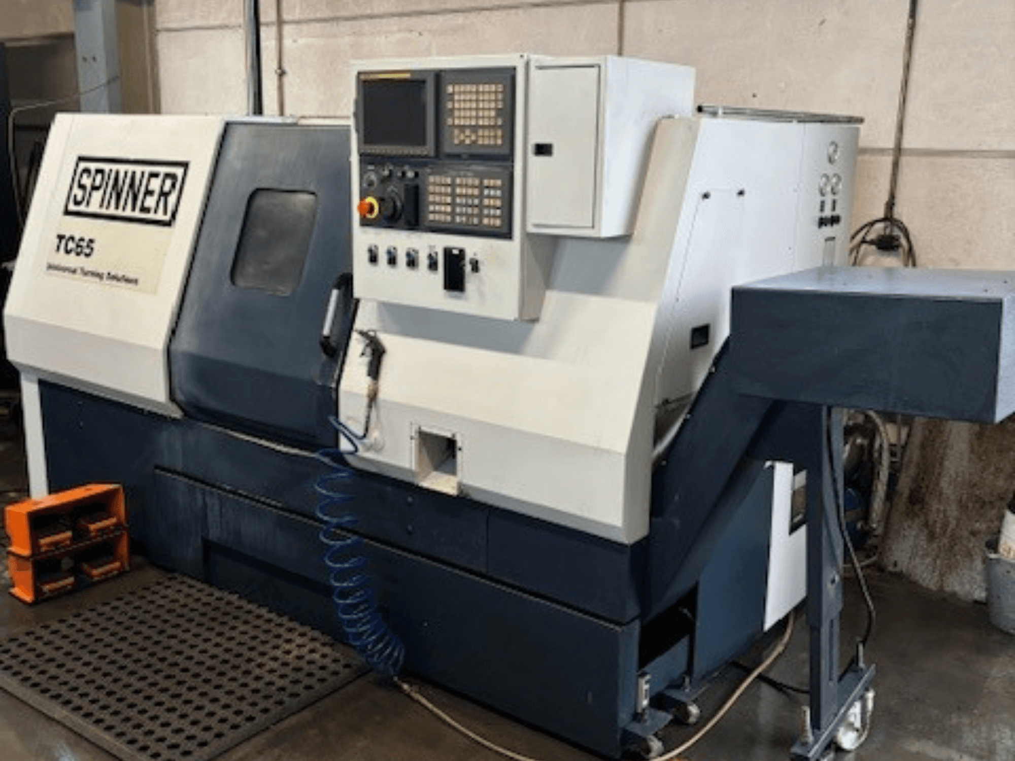 Spinner TC65 industriële draaimachine, vooraanzicht, met bedieningspaneel, persluchtleiding en opbergruimte voor gereedschap.