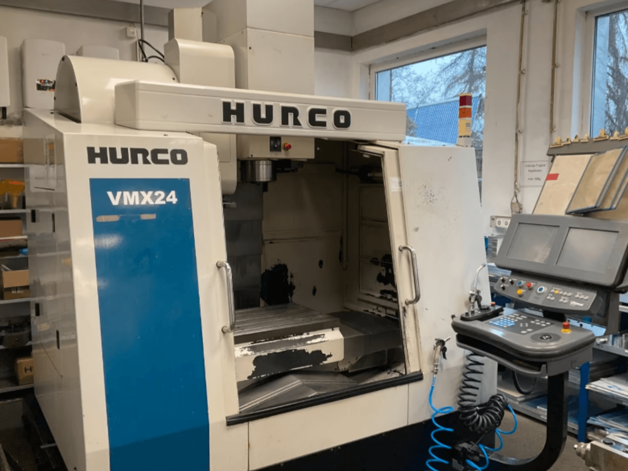 Verticaal bewerkingscentrum Hurco VMX24 in vooraanzicht, met daarop het bedieningspaneel, de spilkop en het werkgebied, waarbij enige slijtage zichtbaar is.