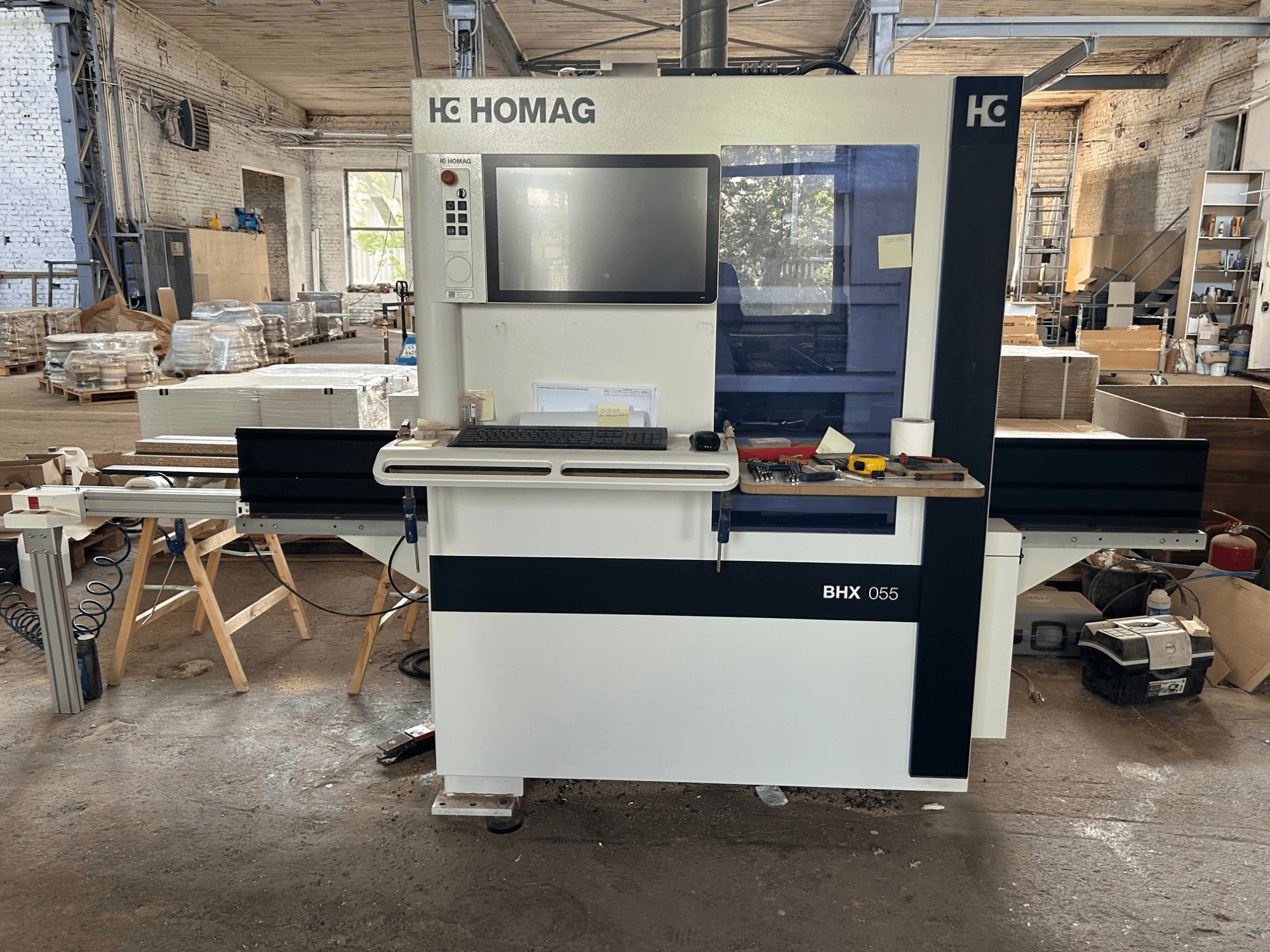 HOMAG WEEKE OPTIMAT BHX 055 CNC-bewerkingscentrum, vooraanzicht, met het bedieningspaneel en het werkgebied met gereedschappen.