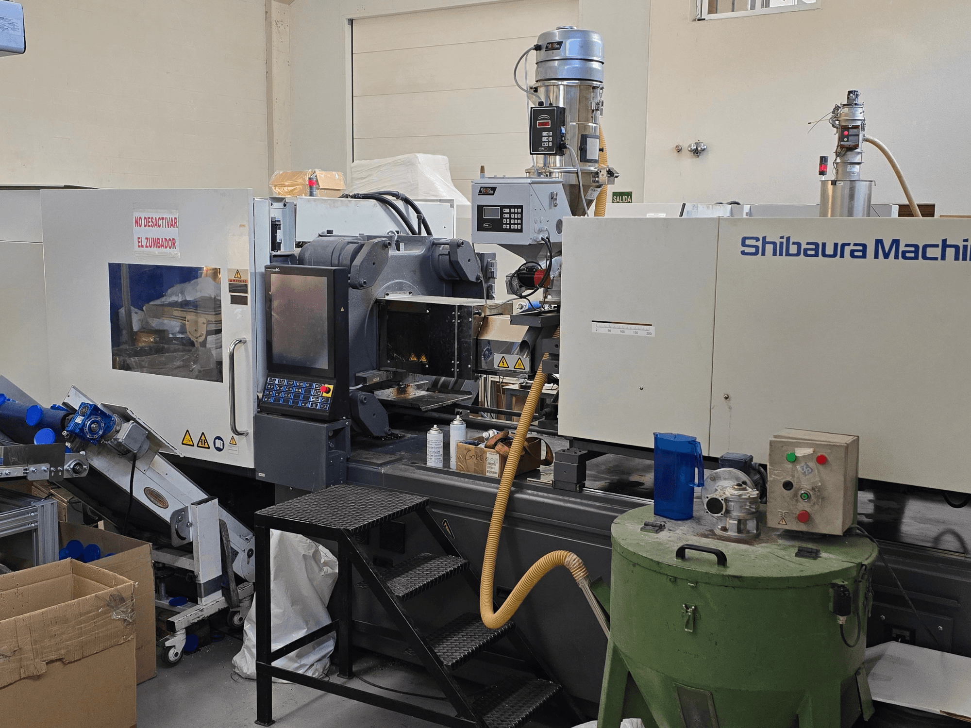 Vooraanzicht van SHIBAURA EC230SXIII-8A elektrische spuitgietmachine met bedieningspaneel en aangrenzende apparatuur.