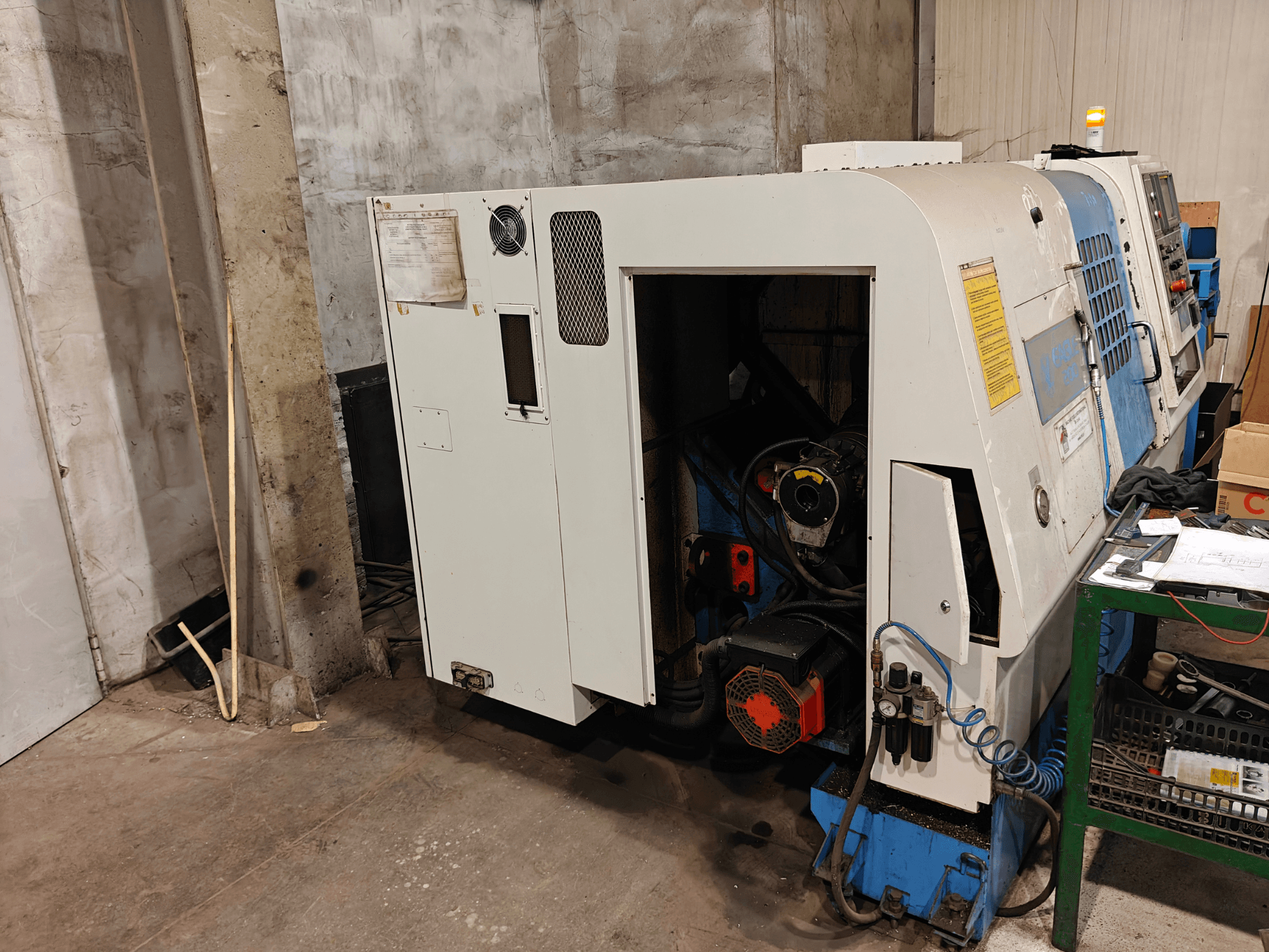 Vooraanzicht van een draaibankmachine, merk en model niet gespecificeerd, met bedieningselementen en zichtbare motoronderdelen.