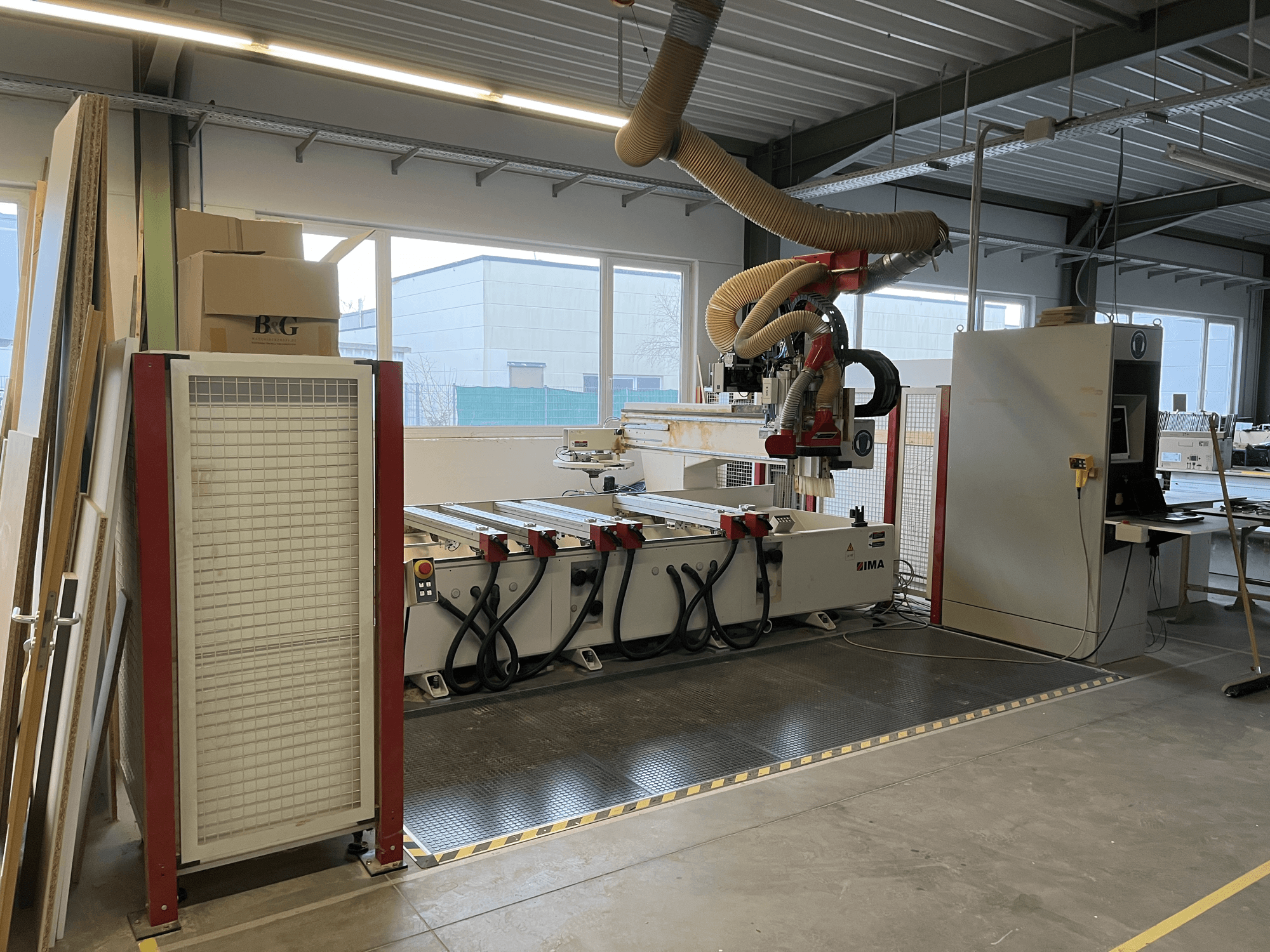 CNC houtbewerkingscentrum IMA BIMA 410 in werkplaats, zijaanzicht met bedieningspaneel en stofafzuigsysteem zichtbaar.