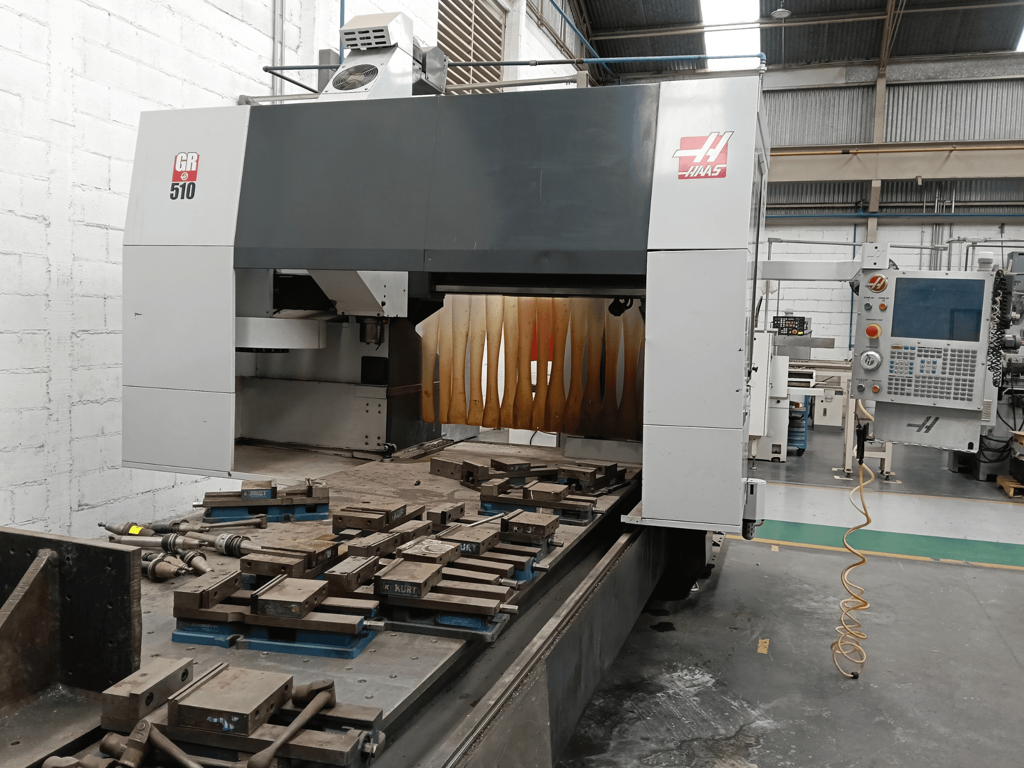 Vooraanzicht van de HAAS GR-510 portaalfreesmachine, met het bedieningspaneel en de bewerkte werkstukken op de tafel.