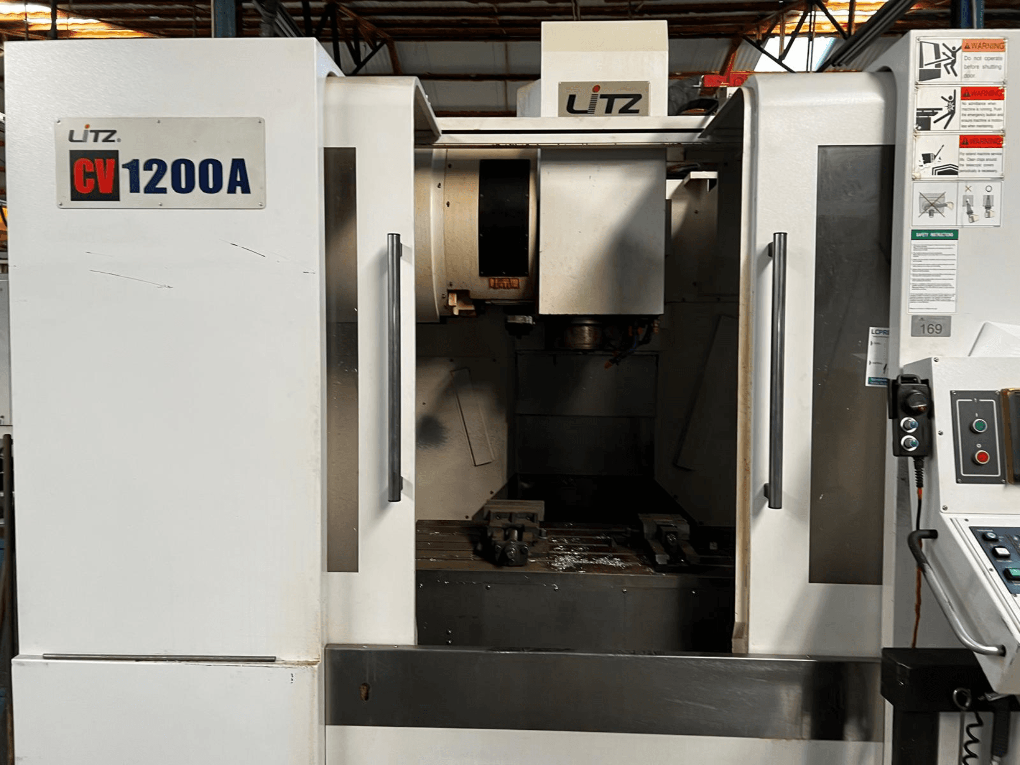Litz CV1200A verticaal bewerkingscentrum, vooraanzicht, met weergave van het bedieningspaneel, de spil en de geopende deur waardoor het werkgebied zichtbaar is.