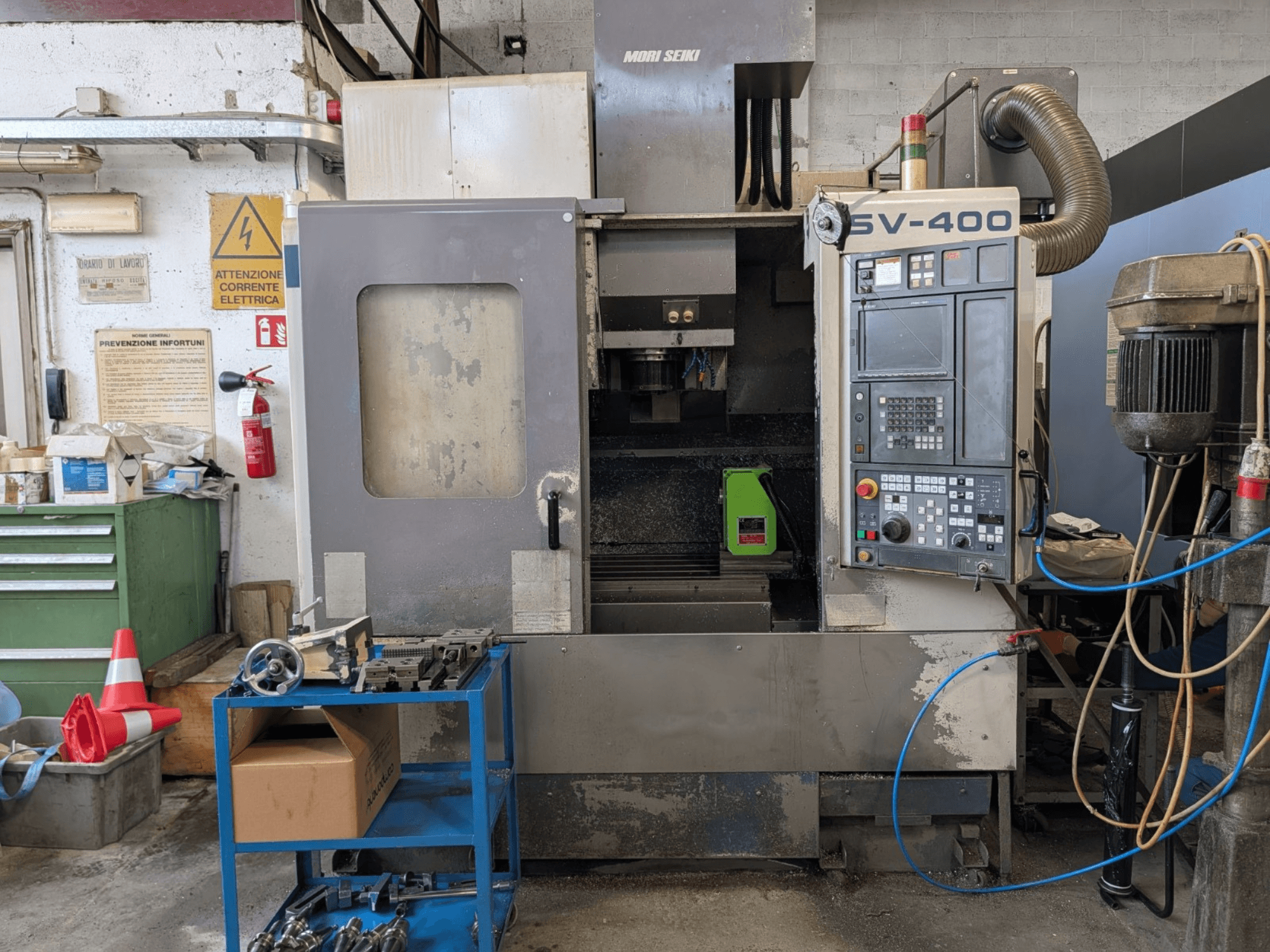 MORI SEIKI SV-400 verticaal bewerkingscentrum in een werkplaats, zijaanzicht, met het bedieningspaneel en de gereedschapsmachines vlakbij.
