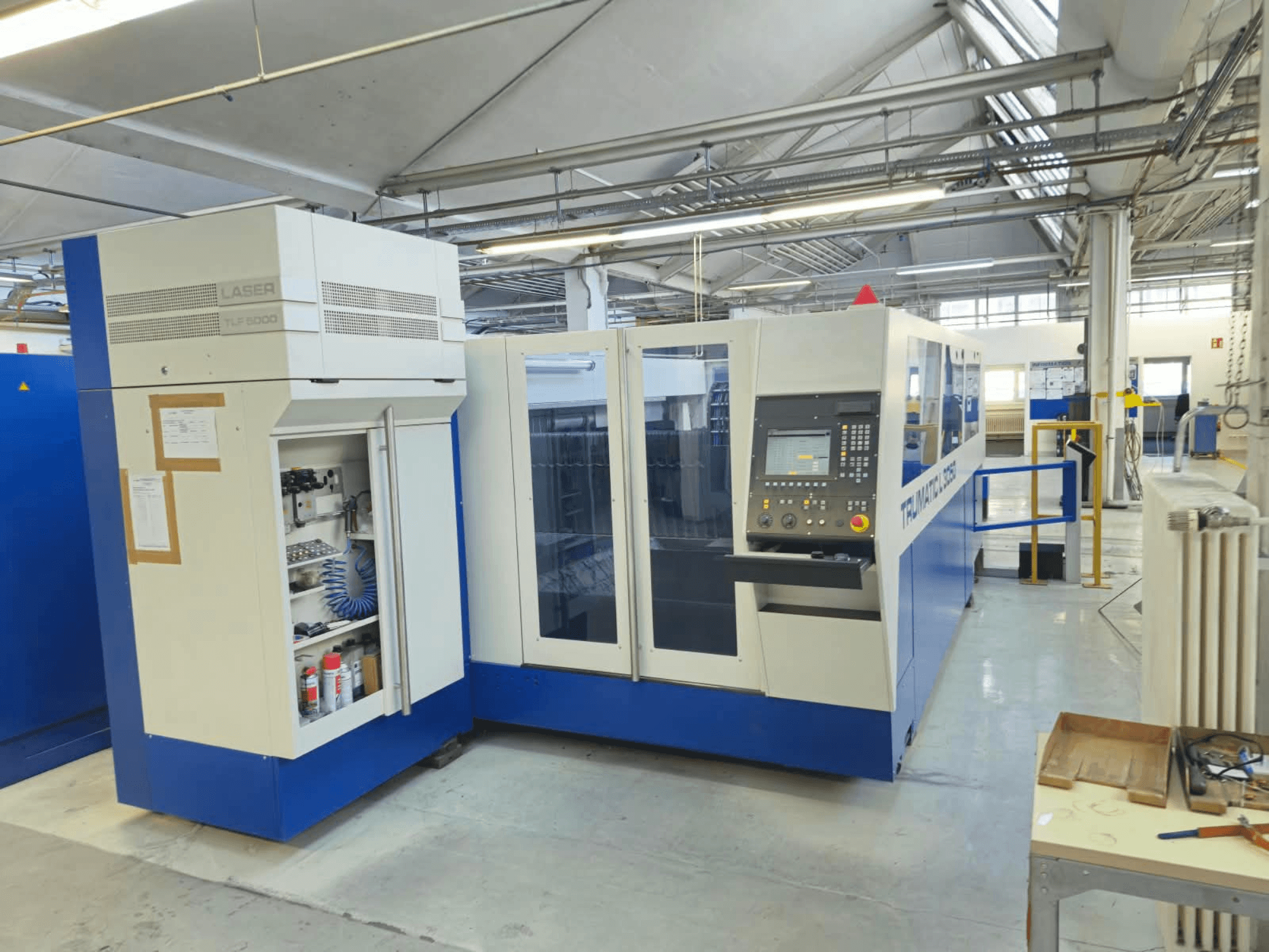 TRUMPF TruLaser L3050 CO₂-lasersnijmachine, vooraanzicht, met bedieningspaneel en onderhoudsklep, in fabrieksinstelling.