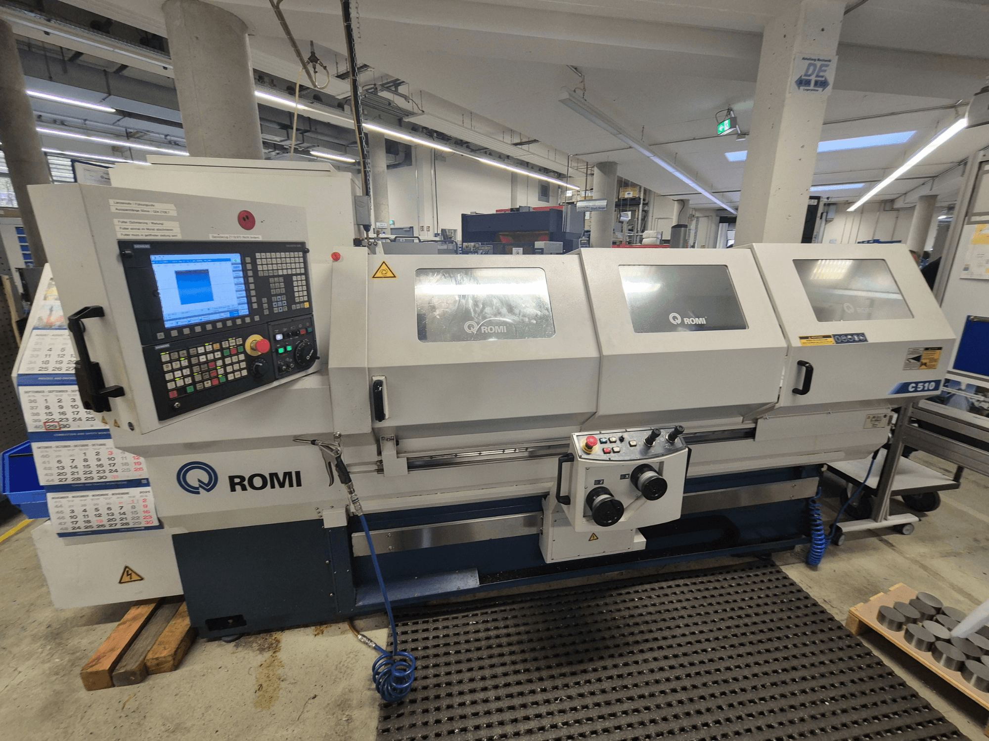 Romi C510 draaibank gezien vanaf de voorkant, met een digitaal bedieningspaneel en drie beschermkappen. Inclusief waarschuwingslabels.