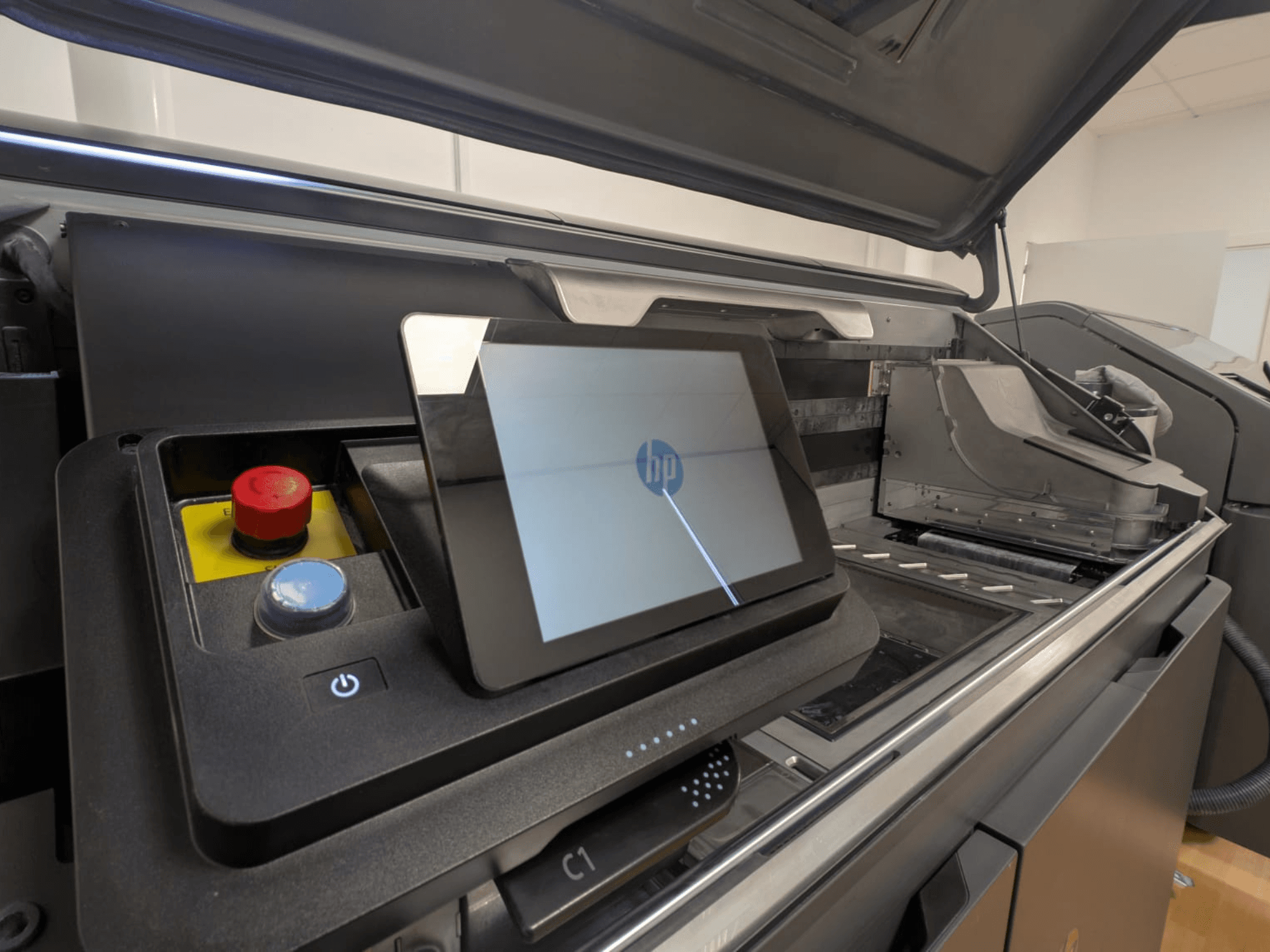 HP printerbedieningspaneel met een tabletdisplay, rode en blauwe knoppen en een zijaanzicht van de interne onderdelen van de printer.