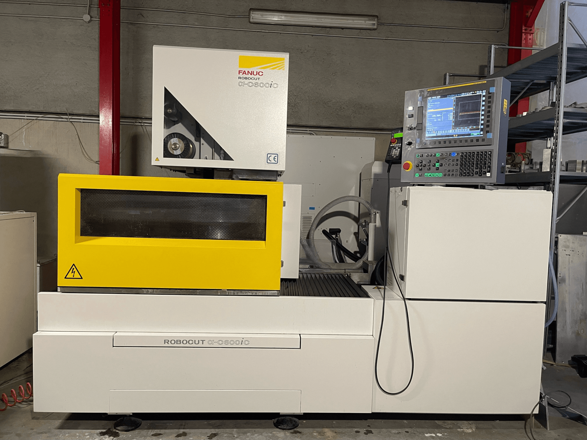 FANUC Robocut α-C600iC, zijaanzicht van CNC machine met gele veiligheidskap en bedieningspaneel, die het precisiesnijvermogen toont.