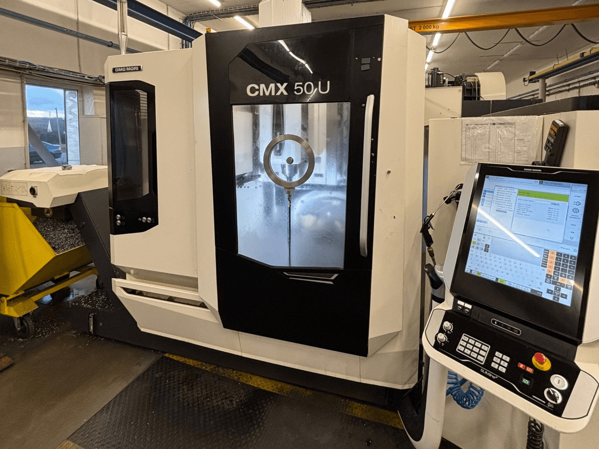 DMG MORI CMX 50 U verticaal bewerkingscentrum, vooraanzicht met bedieningspaneel en glazen display, waarop de interne mechanica te zien is.