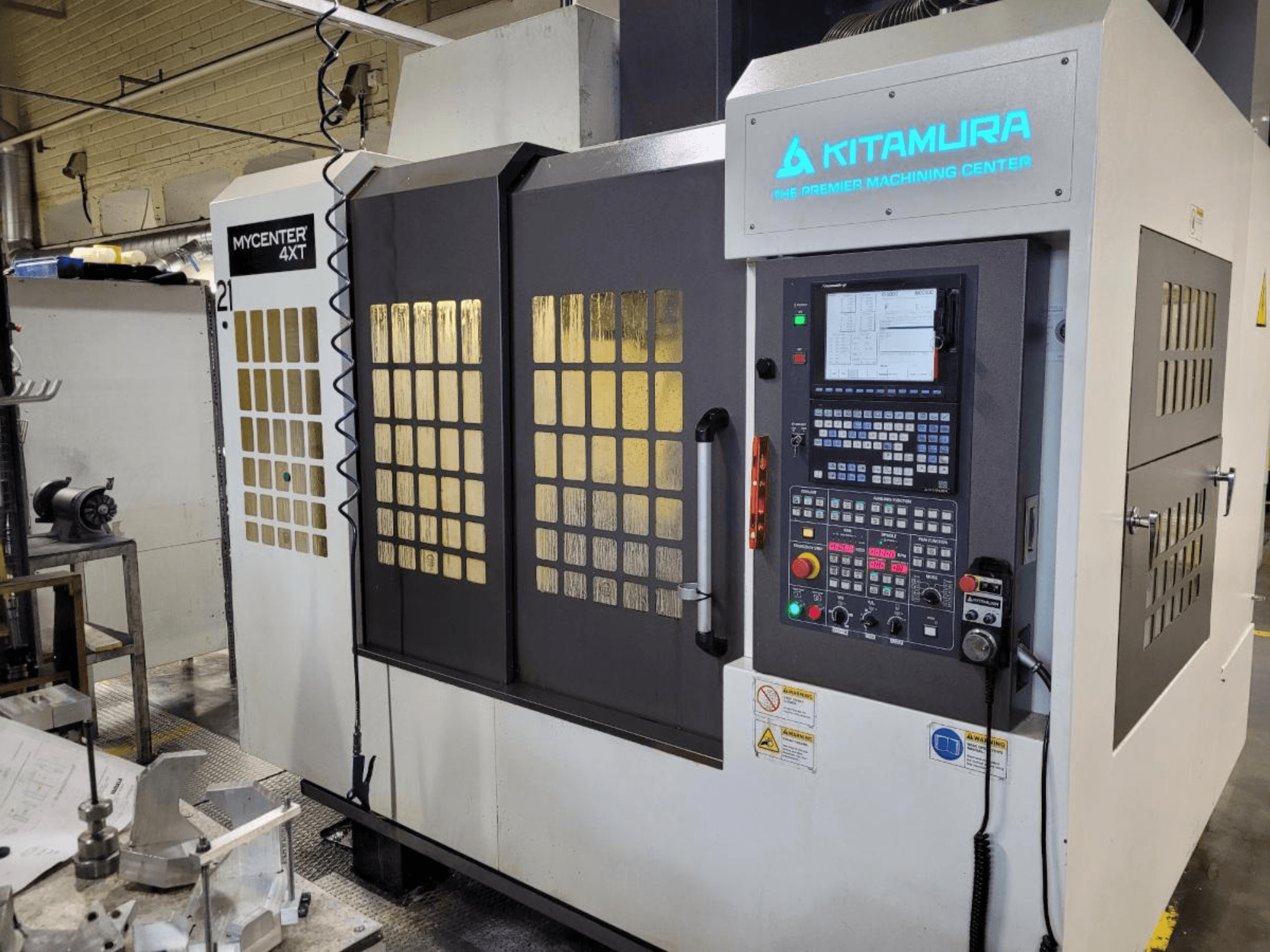 Verticaal zicht op een Kitamura Mycenter-4XT bewerkingscentrum, met bedieningspaneel en verlichte opschriften.