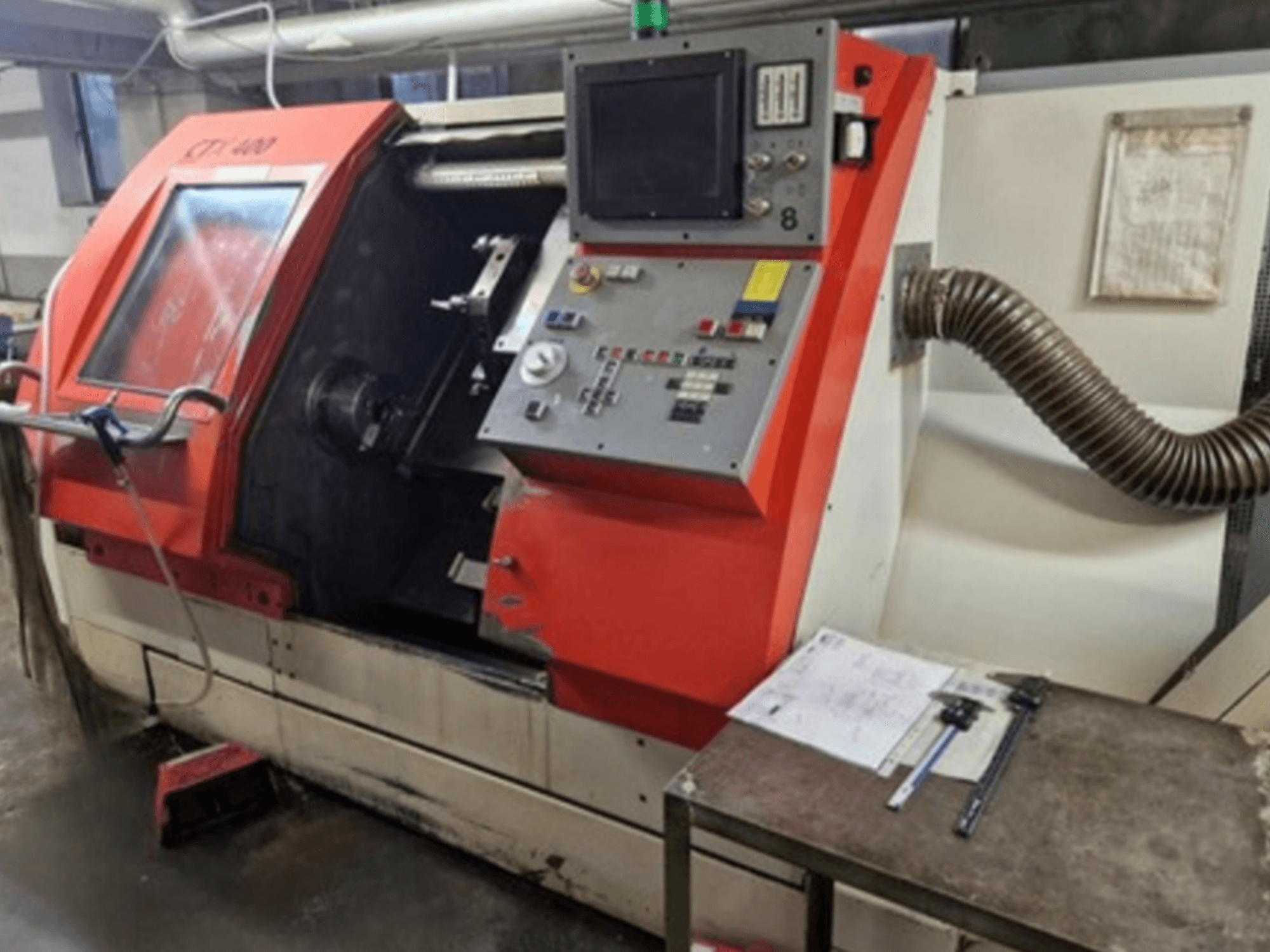 Gildemeister CTX 400 horizontale draaimachine in vooraanzicht, met het bedieningspaneel, de open deur en de werkplaatstafel met gereedschap.