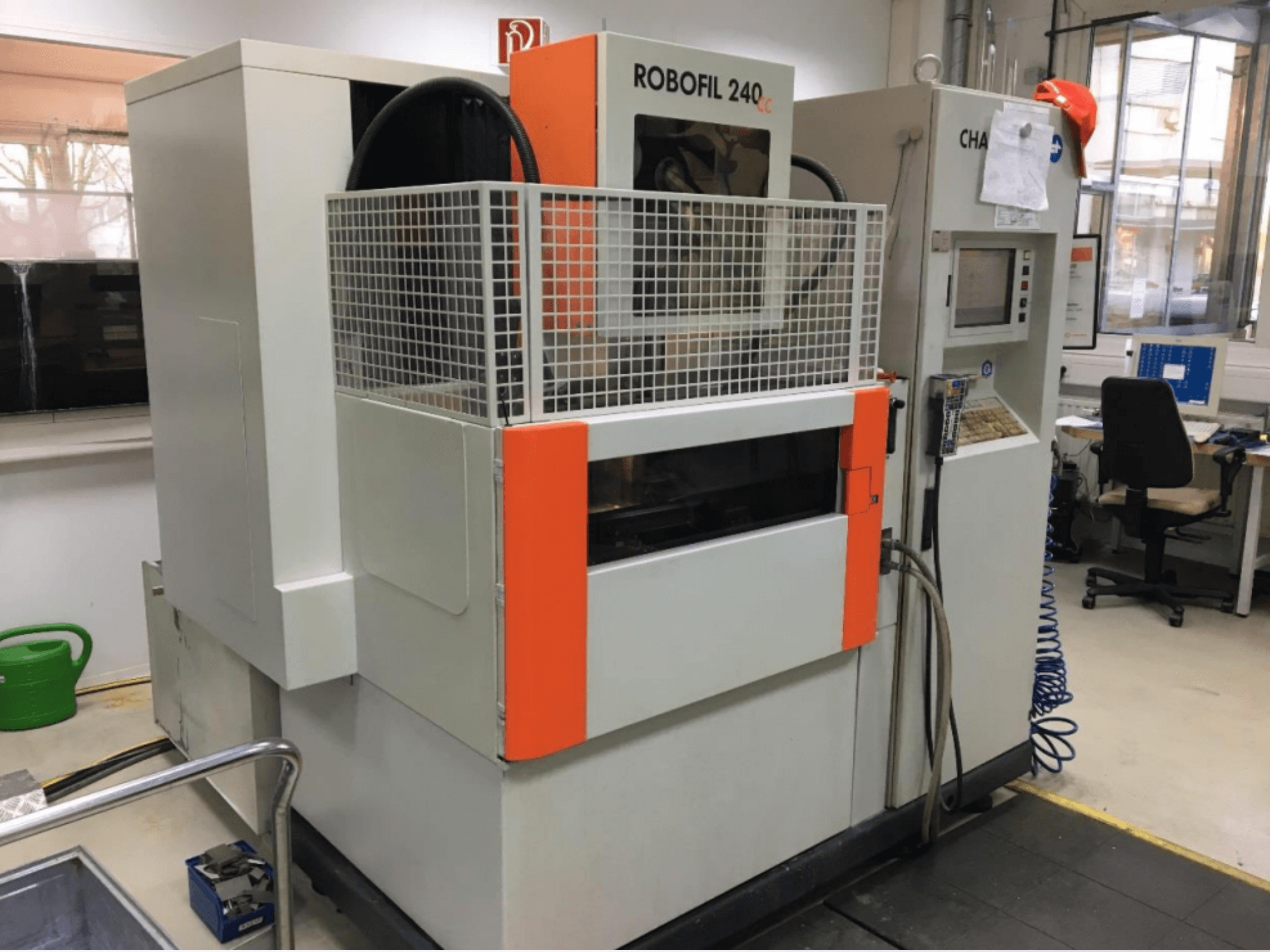 Vooraanzicht van de CHARMILLES ROBOFIL 240 CC draadvonkmachine, voorzien van een beschermrooster en een bedieningspaneel, in een werkplaats.