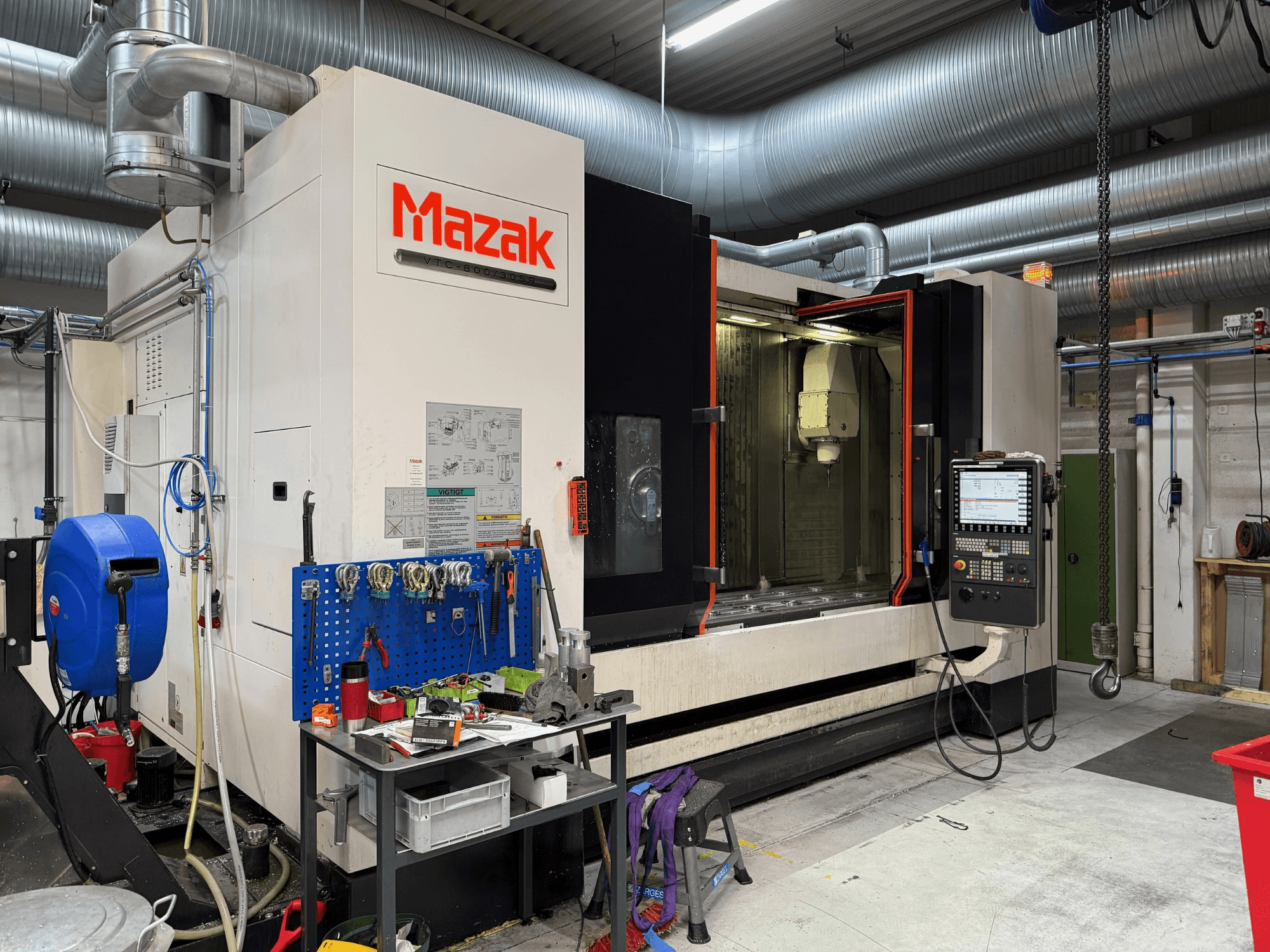 Mazak CNC machine in vooraanzicht, met bedieningselementen, gereedschappen en werkruimte in een bewerkingsomgeving.