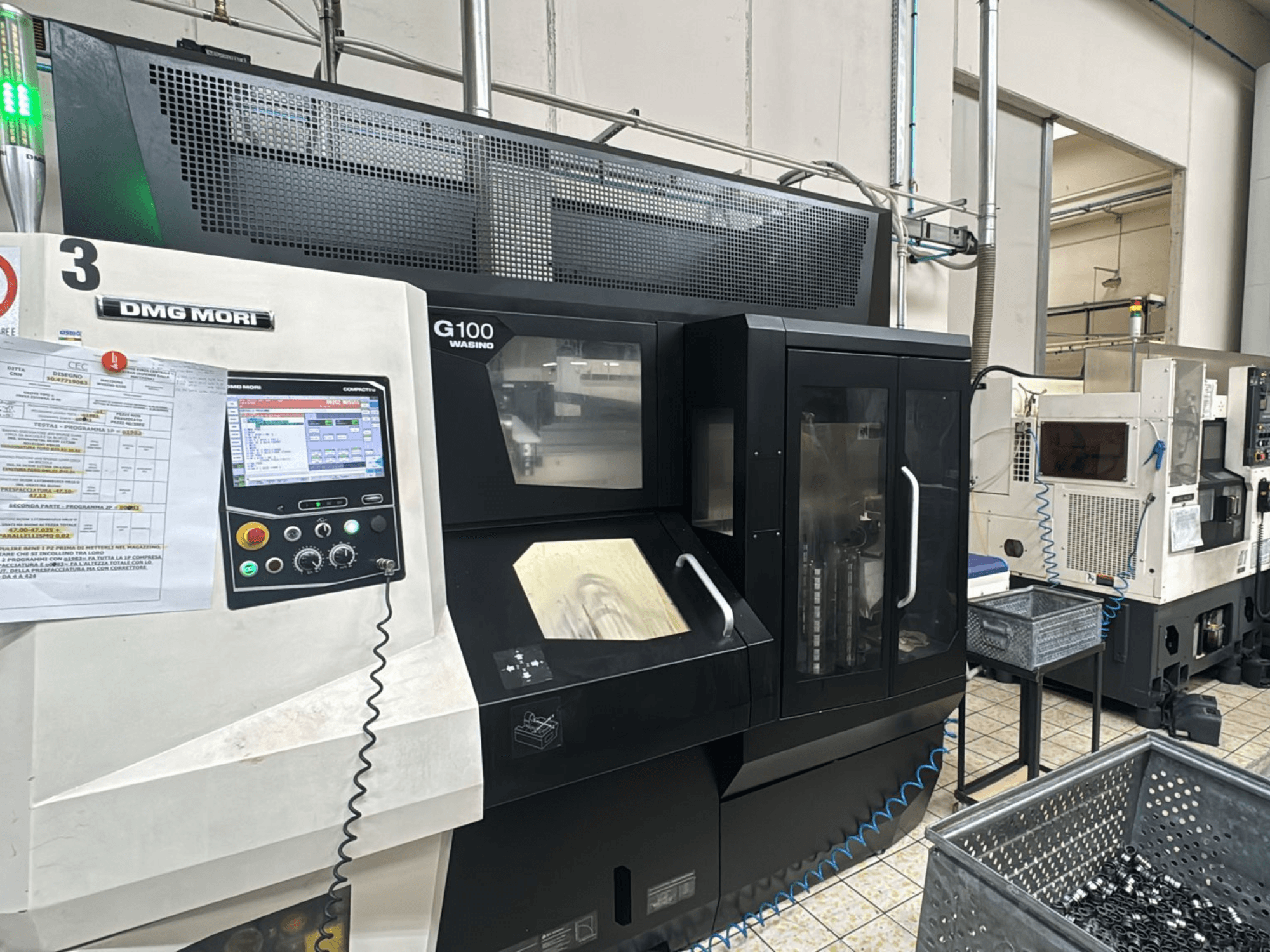 DMG MORI G100 machine in een fabriek, vooraanzicht, met een digitaal bedieningspaneel en nabije opbergbakken voor gereedschap.