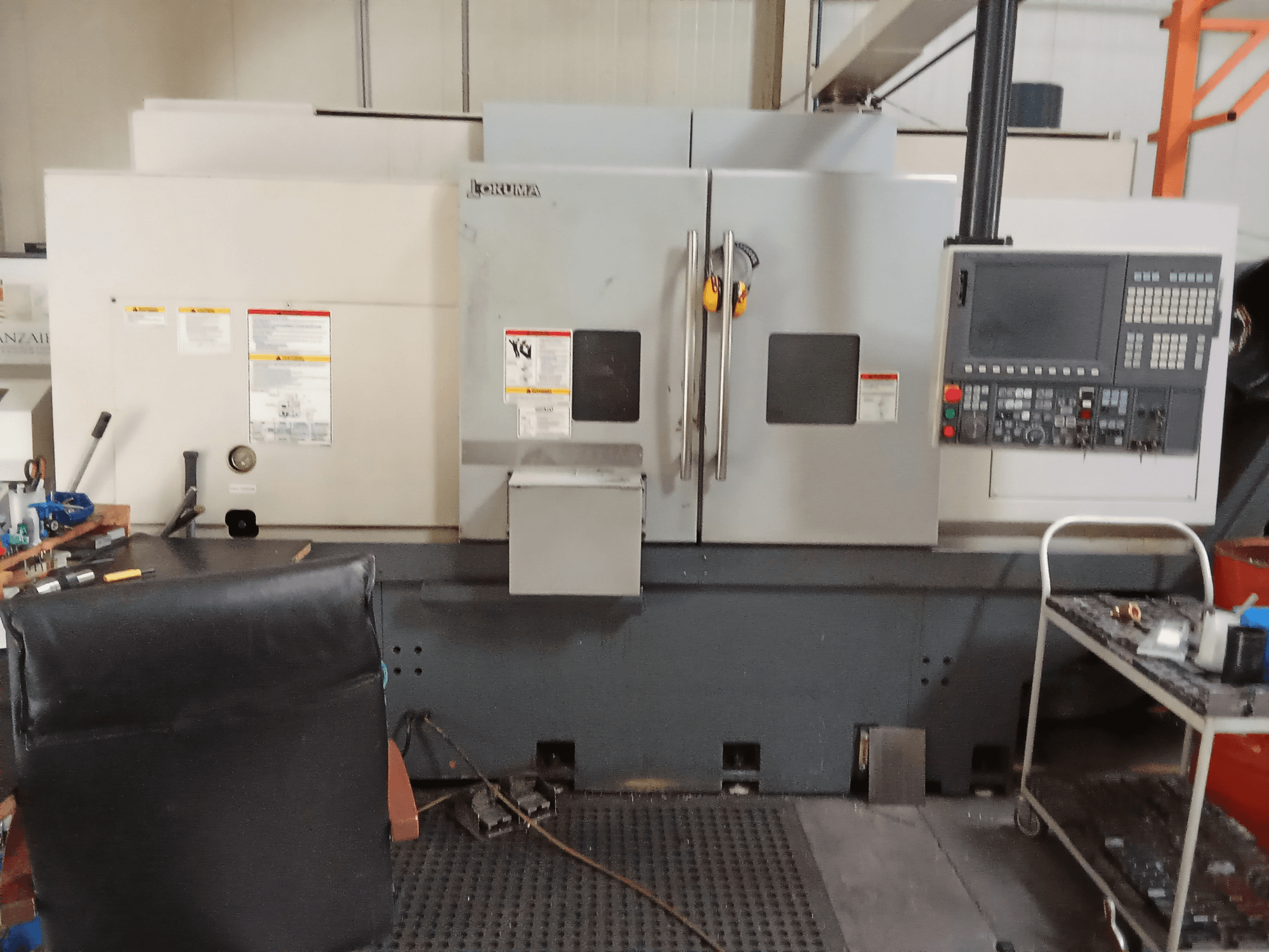 Okuma Genos L300 E-M horizontale draaimachine in vooraanzicht, met bedieningspaneel en dubbele deuren, opgesteld in een werkplaatsomgeving.