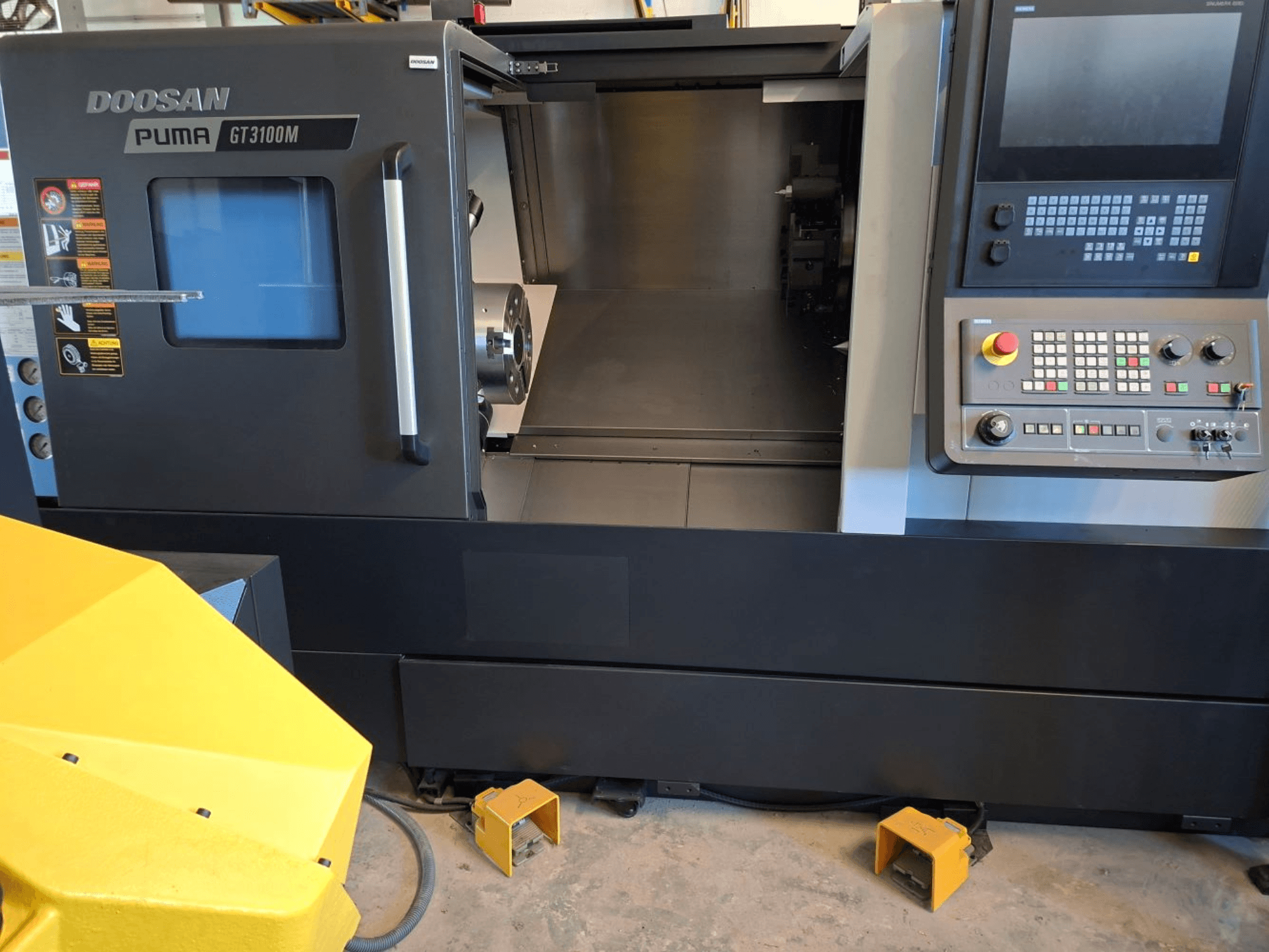 DOOSAN Puma GT 3100 M horizontale draaimachine in vooraanzicht, met het bedieningspaneel, de open revolver en de werkruimte aan de binnenkant.