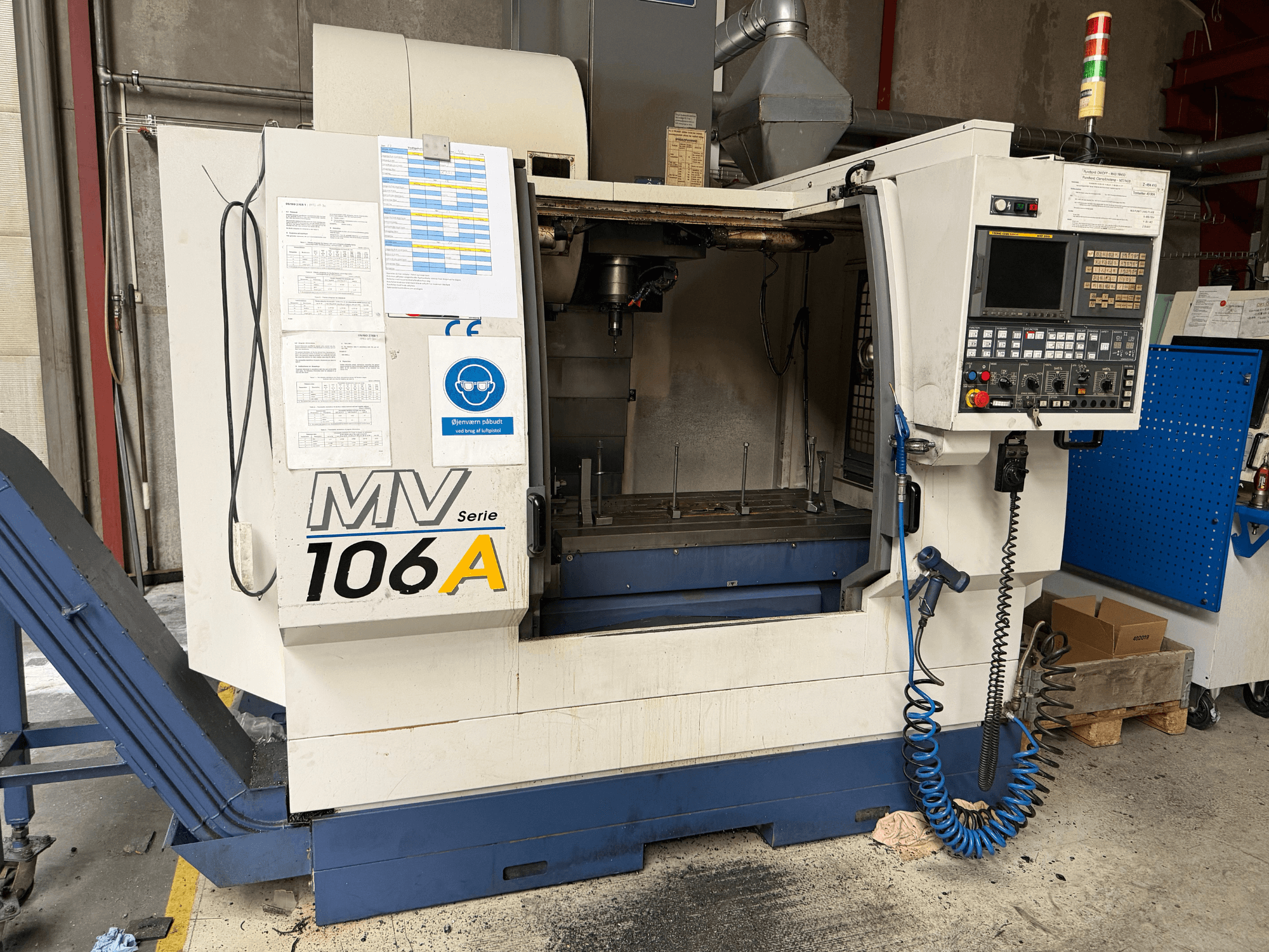 YCM MV106A verticaal bewerkingscentrum, vooraanzicht met bedieningspaneel en werkruimte, inclusief bijgevoegde technische documentatie.