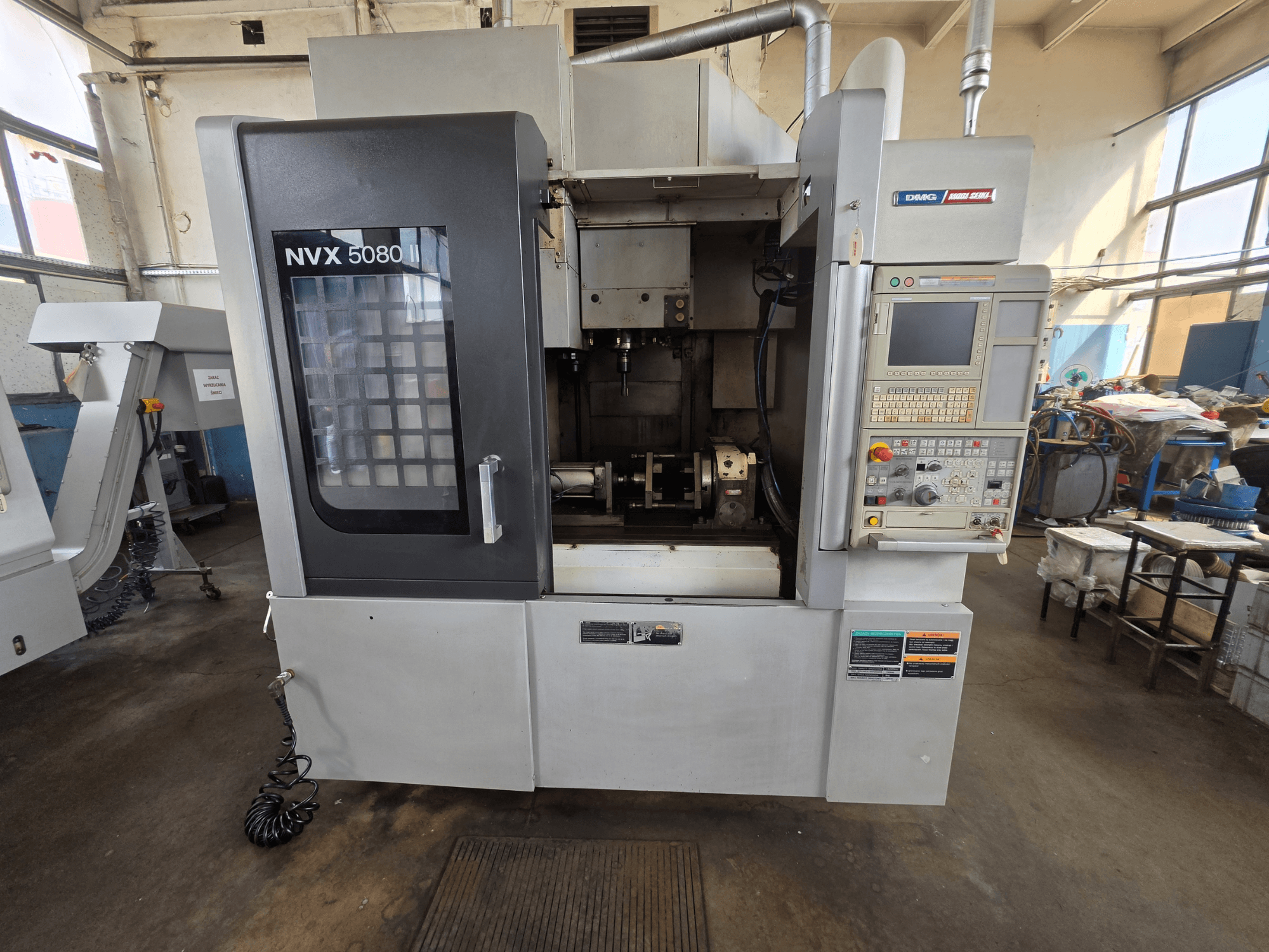 Vooraanzicht van het verticale bewerkingscentrum DMG Mori Seiki NVX 5080 II/40 met bedieningspaneel en doorzichtig venster, waardoor het bewerkingsgebied goed zichtbaar is.
