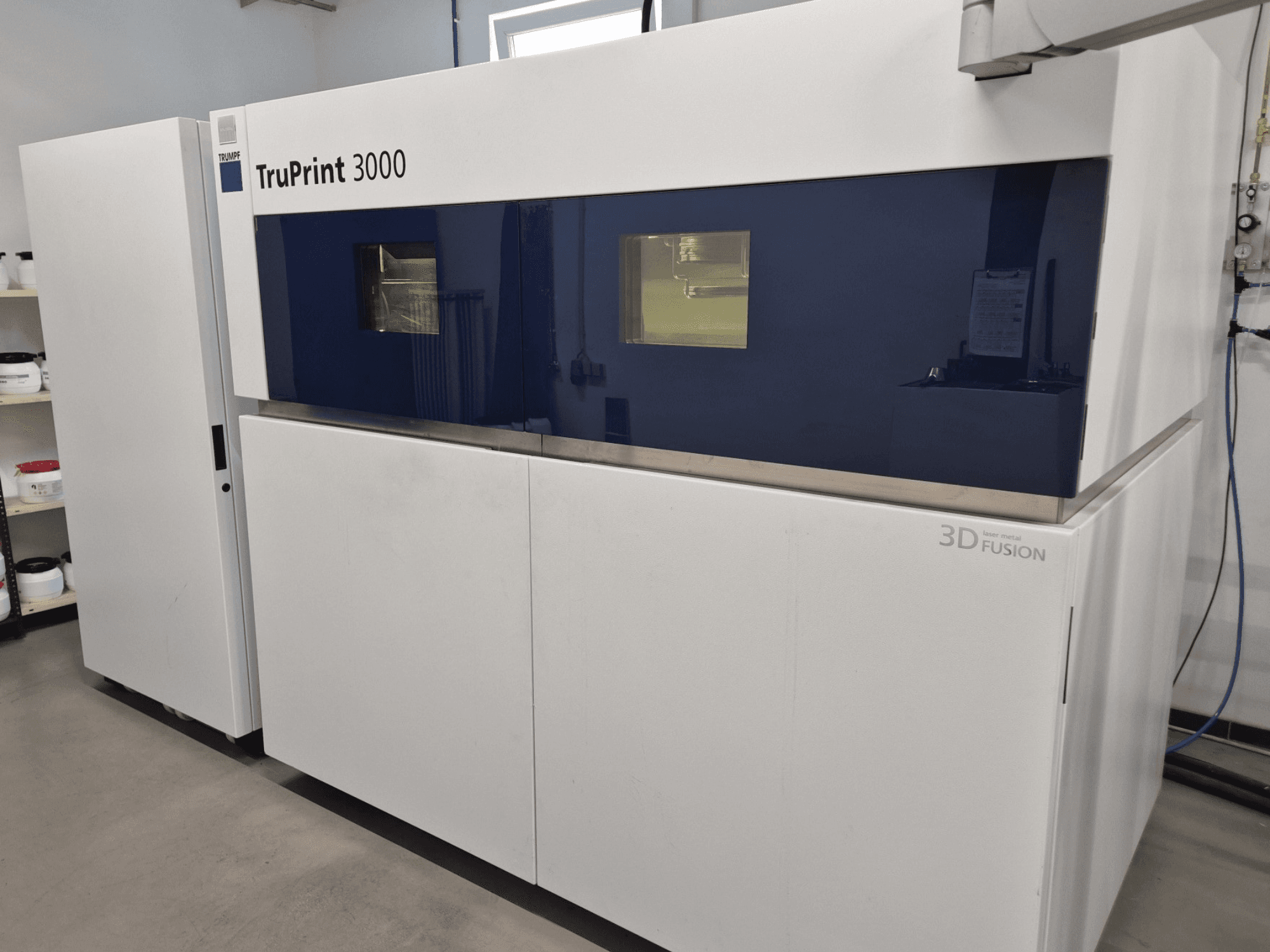 TruPrint 3000 metalen 3D printer in vooraanzicht, met een ontwerp met blauwe panelen en laserfusietechnologie.