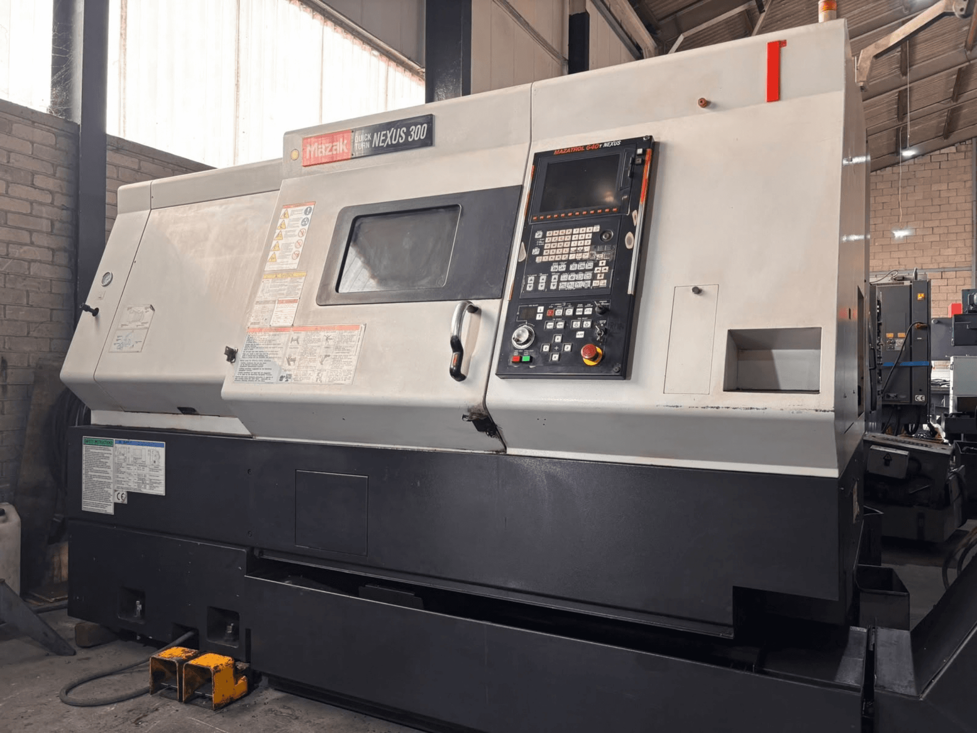 Mazak QT NEXUS 300 horizontale draaimachine, zijaanzicht met bedieningspaneel en bedrijfsindicatoren in een werkplaatsomgeving.